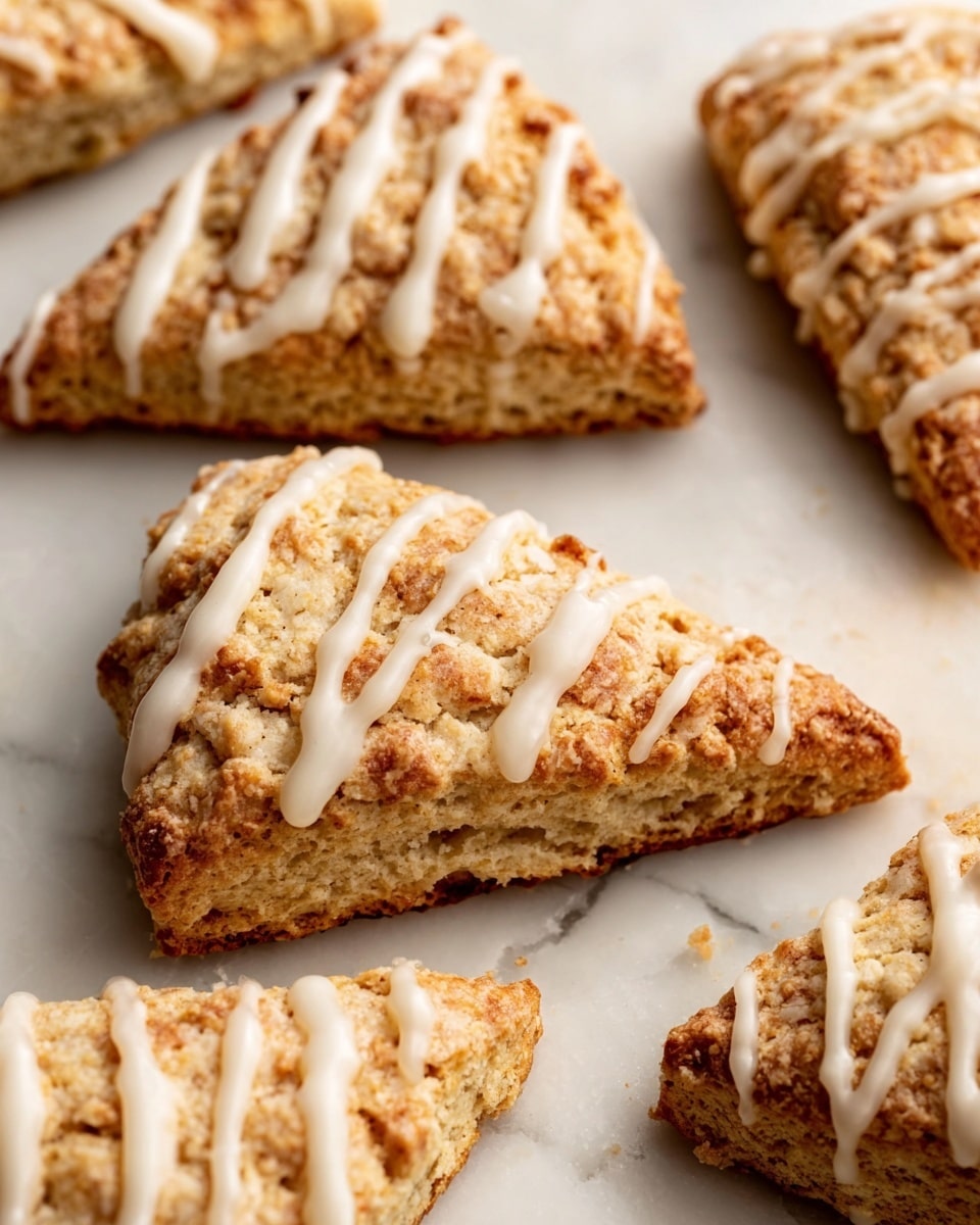 The image shows several triangular scones arranged on a white marbled surface. Each scone has a golden-brown top with a crumbly texture, and they are topped with a smooth, white icing that is drizzled in thin diagonal lines across each scone. The scones have uneven edges, showing a soft, flaky inside. The lighting highlights the warm colors and the glossy icing, making the texture of the scones clear. photo taken with an iphone --ar 4:5 --v 7