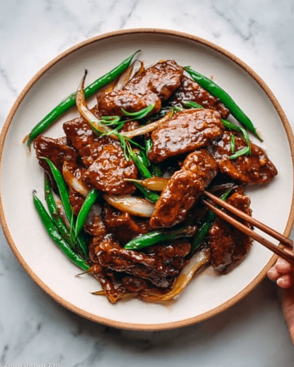 The image shows a white plate filled with a dish of meat covered in a shiny brown sauce. The meat pieces are thick and laid on a bed of stir-fried green beans and onion slices, which have a soft texture and pale color. The sauce coats the meat and vegetables evenly, giving a rich look. A woman's hand is holding a pair of wooden chopsticks picking up a piece of meat. The plate is placed on a white marbled surface. photo taken with an iphone --ar 4:5 --v 7