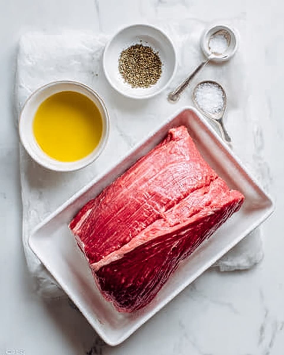 A large piece of raw red meat with marbling sits in a white rectangular tray on a white marbled surface. Beside it, there is a small white bowl filled with yellow oil, a small white bowl with black pepper, and a white bowl of salt with a small silver spoon on top. The scene is clean and bright with soft natural light highlighting the textures of the meat and the smooth surface of the bowls. Photo taken with an iphone --ar 4:5 --v 7