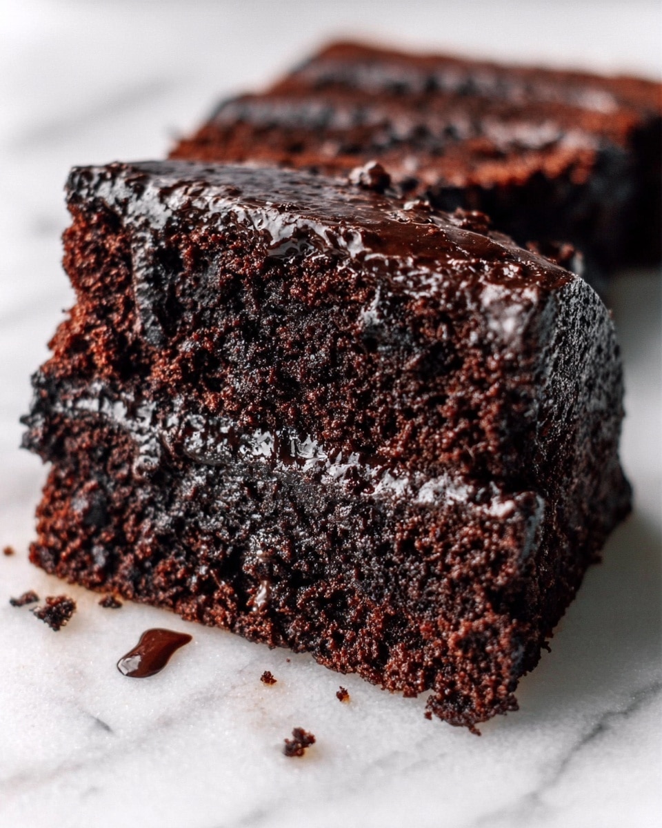 The image shows a close-up of two slices of rich, dark chocolate cake placed on a white marbled surface. Each slice has multiple moist layers of deep brown cake with visible small chunks of chocolate inside. On top, there is a thick layer of glossy, dark chocolate icing that looks slightly shiny and smooth, with bits of melted chocolate slightly dripping down the sides. The texture of the cake looks soft and dense, and the edges appear slightly crumbly. photo taken with an iphone --ar 4:5 --v 7