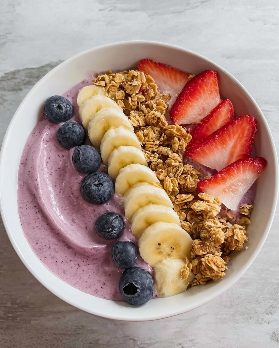 A white bowl sits on a white marbled surface, filled with three main layers. The bottom layer is smooth and creamy, light purple in color, taking up the center space. Along the bottom edge of the bowl, there are evenly placed slices of banana, light yellow and soft in texture. On the left of the purple layer, small round blueberries are placed in a neat line, deep blue with a shiny finish. On the top right, there are thin strawberry slices, bright red with white and green tips, next to a heap of crunchy golden-brown granola. The colors create a fresh and healthy look. Photo taken with an iphone --ar 4:5 --v 7