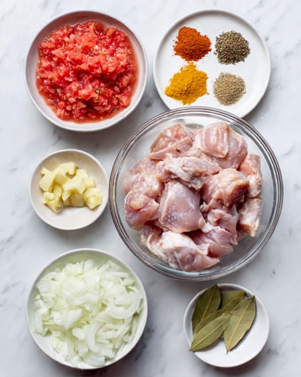 The image shows ingredients for a dish arranged on a white marbled surface. There is a large clear bowl in the center filled with raw, skinned pieces of chicken, light pink with some white fat. Surrounding this bowl, at the top left is a white bowl with finely crushed fresh tomatoes, red and watery in texture. To the top right, a white plate holds six different dry spices grouped neatly, showing colors like dark brown, orange-red, pale beige, and bright yellow powders arranged in small piles. At the bottom left is a white bowl filled with roughly sliced white onions. At the bottom right is another white bowl containing two bay leaves and chopped ginger in small pieces, pale yellow in color. The overall layout is tidy and colorful, with all items clearly separated. Photo taken with an iphone --ar 4:5 --v 7