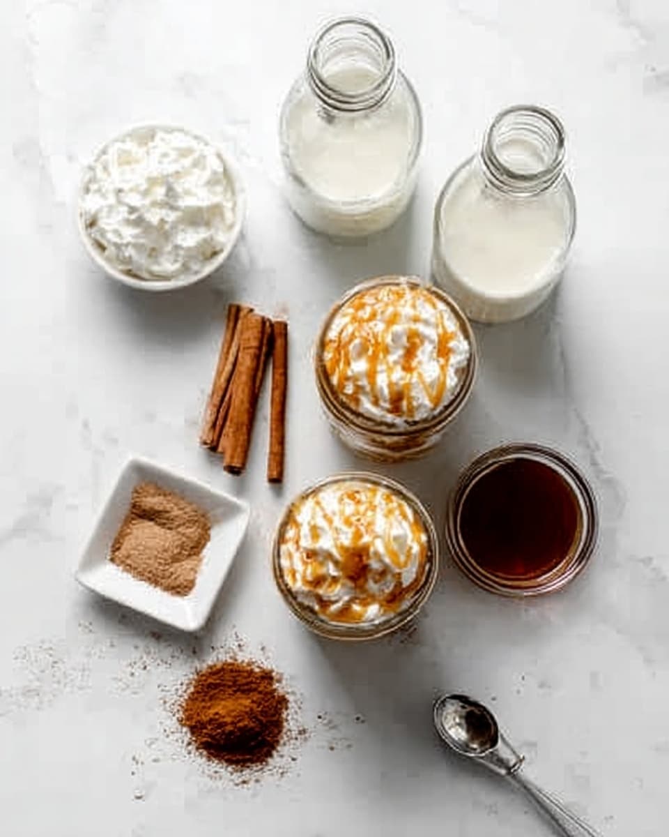 The image shows two glass jars with whipped cream on top, drizzled with caramel sauce, placed side by side on a white marbled surface. Around the jars are three clear glass bottles, one filled with milk, the other two empty. To the left is a small white square bowl filled with white cream. Below the jars are two cinnamon sticks and a white round bowl with brown cinnamon powder and a small brown heart shape in the middle. To the right is a small pile of dark brown powder next to a silver measuring cup and a spoon resting in a dark brown liquid in a small transparent bowl. Photo taken with an iphone --ar 4:5 --v 7