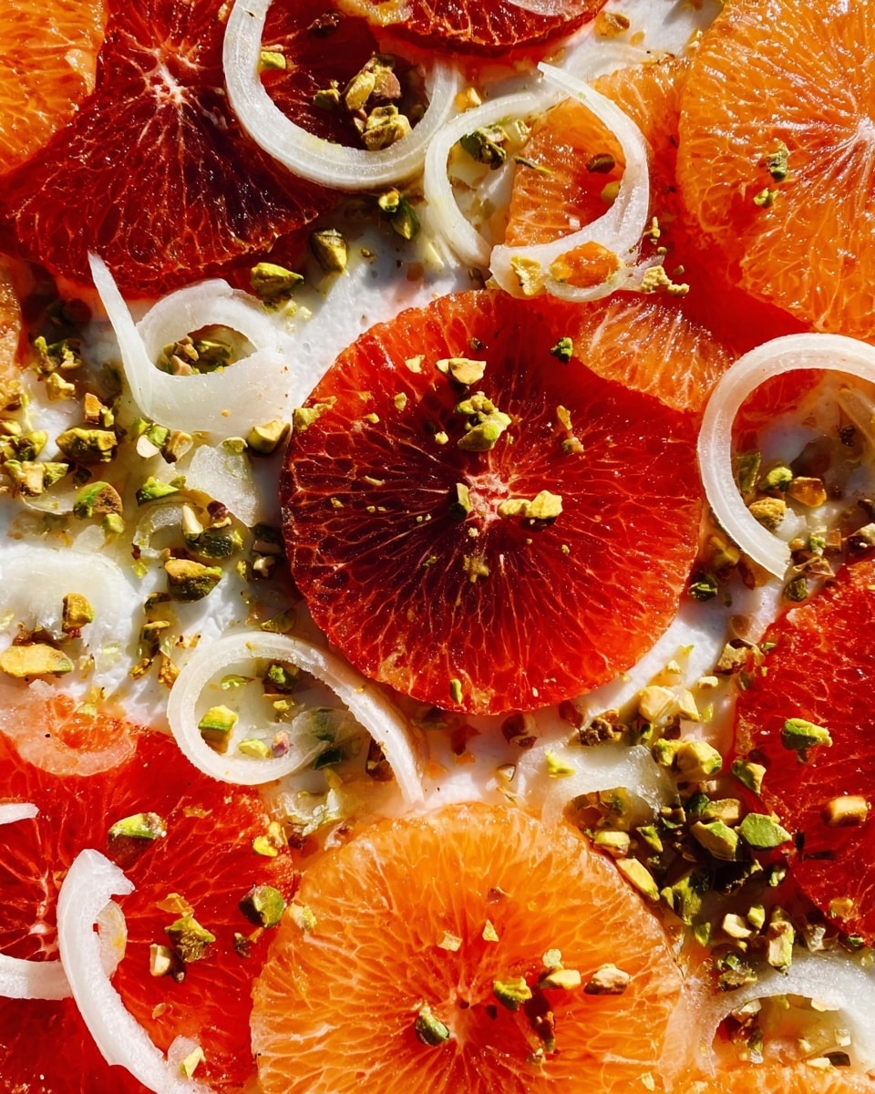 The image shows a close-up of a salad with many layers. The bottom layer has thin, round slices of red and orange citrus fruits spread across a white marbled surface. On top of this, there is a layer of thin white onion slices, adding light texture and curves. Scattered on top are bits of small green pistachio nuts, adding little spots of green and rough texture. The overall colors are bright with reds, oranges, white, and green. The bright natural light makes the colors pop, and the details of each ingredient are clear and fresh. Photo taken with an iphone --ar 4:5 --v 7