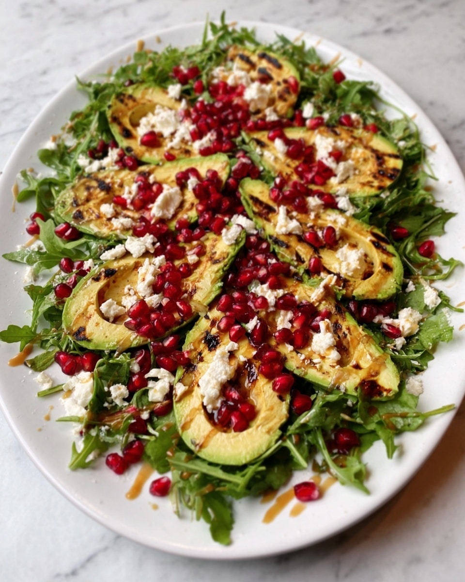 A white oval plate holds a fresh salad with layers of green arugula leaves spread around the edges. On top, grilled avocado halves with charred grill marks are arranged evenly. Over the avocado, there is a layer of white cheese crumbles scattered across the salad. Bright red pomegranate seeds are sprinkled generously all over, adding small pops of color. The salad is finished with a drizzle of a light brown dressing on top. The plate is placed on a white marbled surface. Photo taken with an iphone --ar 4:5 --v 7