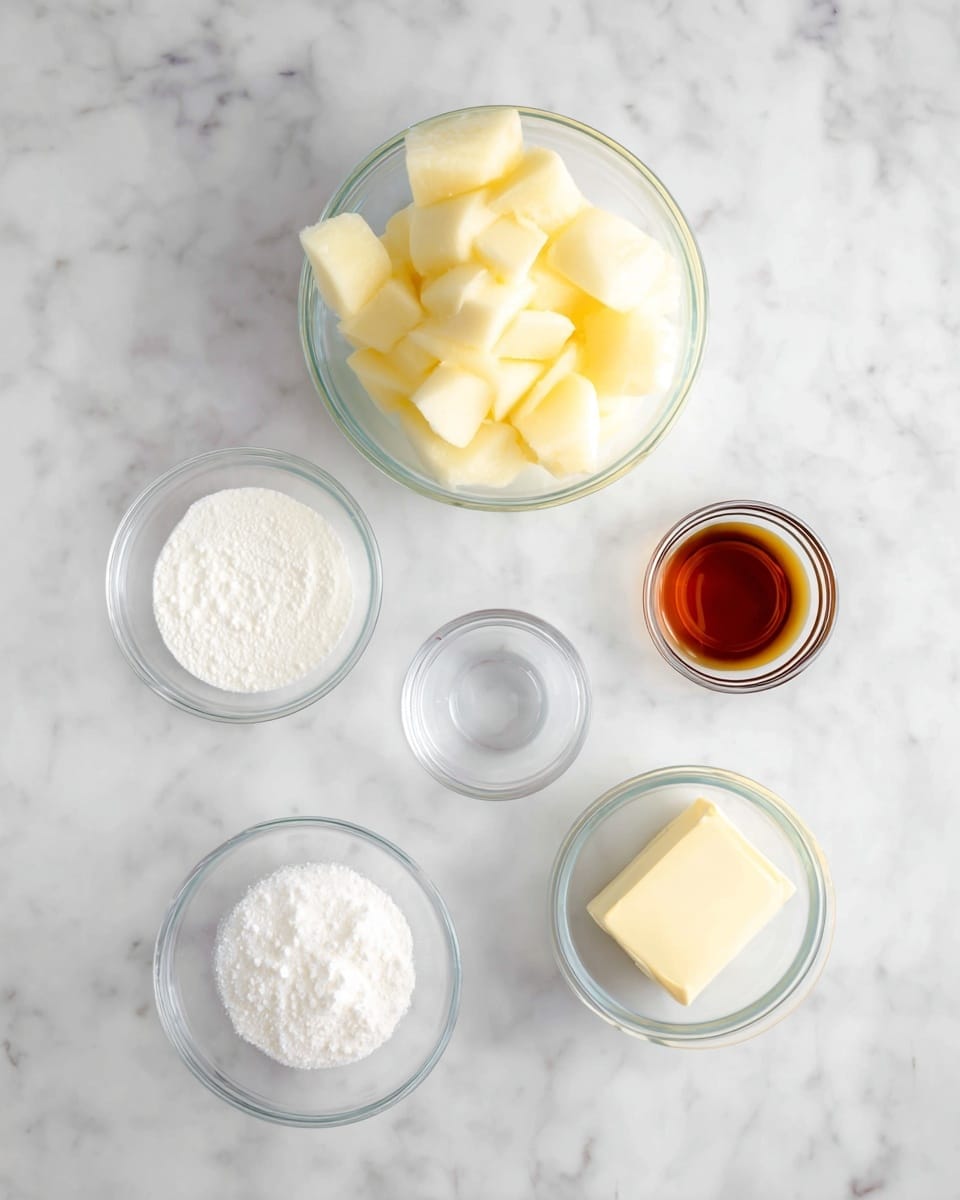 A top view image shows six small glass bowls arranged neatly on a white marbled surface. The largest bowl at the top center holds large, pale yellow chunks of peeled apple. Below it to the left is a small bowl of white powder, likely cornstarch, and to the right a bowl with a dark amber liquid, probably vanilla or syrup. Further down, in the middle, there is an empty glass bowl with a slightly frosted look. On the bottom left is a bowl filled with white granulated sugar, and to the right of it is a smaller bowl containing a square piece of pale yellow butter. All items are clear and clean, emphasizing the fresh ingredients. Photo taken with an iphone --ar 4:5 --v 7
