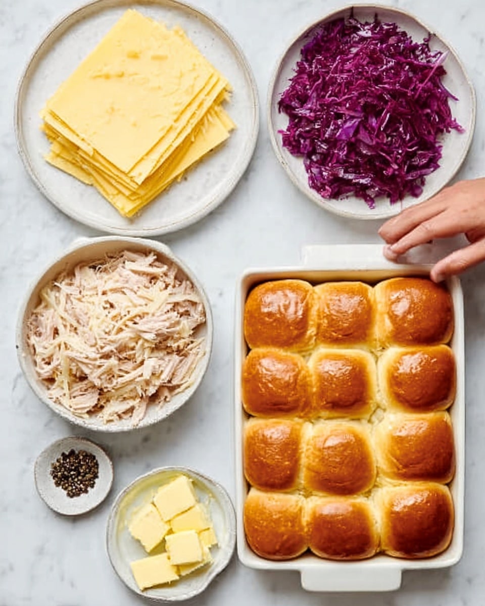 The image shows a white marble surface with four white dishes neatly arranged. In the top left is a plate with a stack of light yellow sliced cheese. To the right, a bowl holds shredded light brown chicken. Below the cheese is a smaller bowl filled with purple shredded cabbage. Next to the cabbage is a small dish with whole black peppercorns, and beside it a small square dish with a few pats of yellow butter. On the bottom right is a white rectangular baking dish filled with nine soft golden brown dinner rolls, arranged in three rows of three. A woman's hand reaches toward the shredded chicken bowl from the top. Photo taken with an iphone --ar 4:5 --v 7