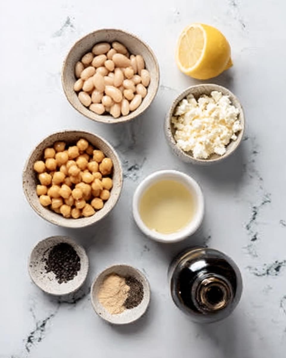 The image shows six small white bowls arranged on a white marbled surface. The top left bowl holds light beige white beans with smooth texture, while the top right bowl contains crumbled white cheese. Below the cheese, there is a white bowl with a tiny amount of pale yellow liquid. To the left of that, a white bowl holds golden chickpeas with a round shape and slightly rough texture. To the left of the chickpeas is a small white bowl with a mix of black and light brown powders. At the bottom, there is a dark bottle with a shiny surface, partially visible. A halved lemon with a bright yellow inside is near the top of the image. photo taken with an iphone --ar 4:5 --v 7