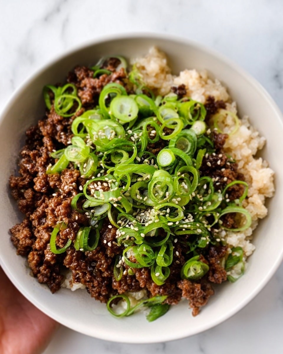 The image shows a close-up of a white bowl filled with a dish that has three main layers. The bottom layer appears to be cooked grains or rice with a light beige color and soft texture. On top of this is a generous layer of brown cooked ground meat, slightly crispy and crumbly. The top layer is fresh, bright green sliced scallions scattered evenly, adding color and freshness. There are also small white sesame seeds sprinkled over everything. The bowl sits on a white marbled surface. A woman's hand is holding the bowl from the side. Photo taken with an iphone --ar 4:5 --v 7