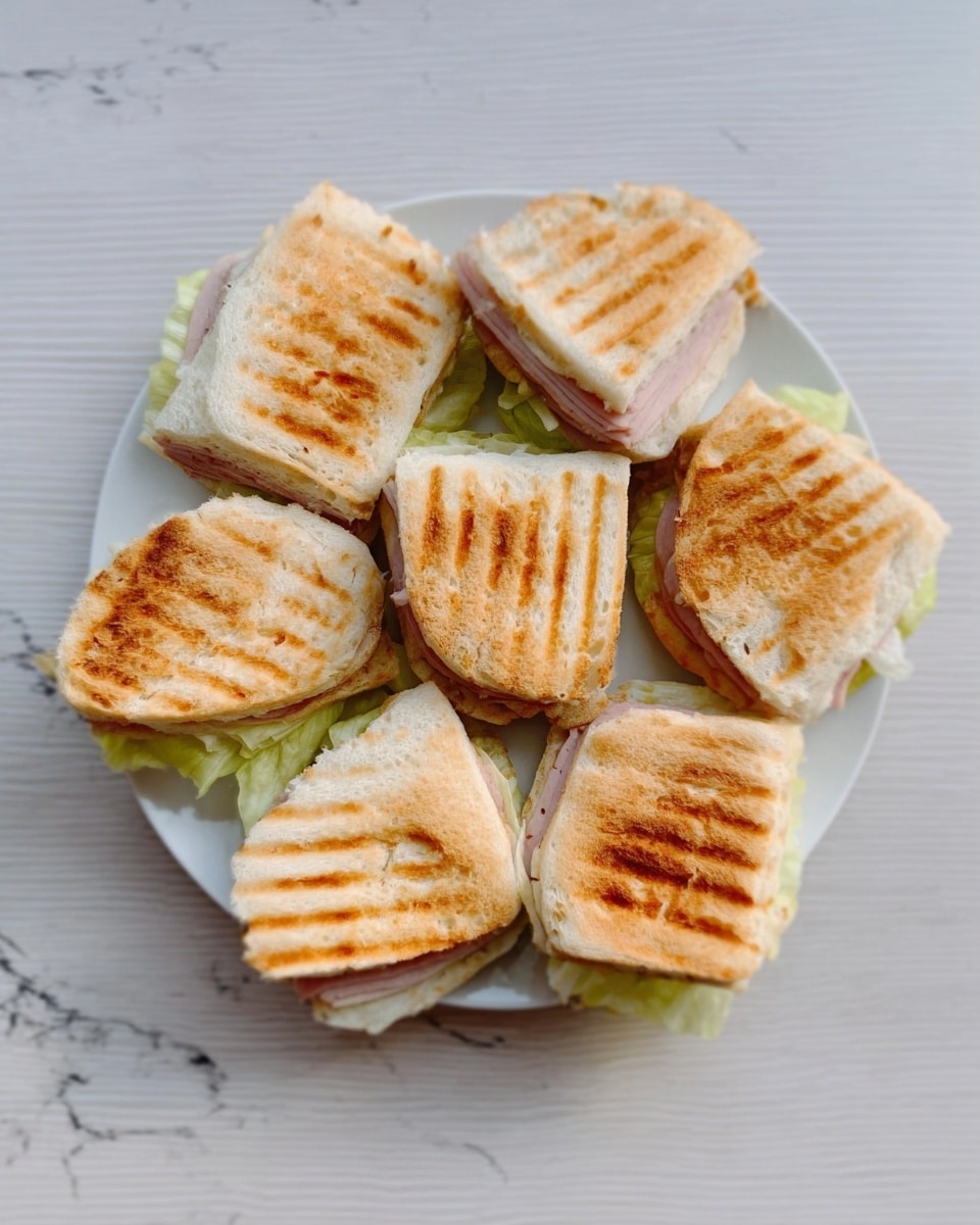 On a white plate, there are six small sandwiches arranged close together. Each sandwich has a top layer of golden-brown grilled bread with visible grill marks and a slightly toasted texture. Below the bread, thin layers of light pink deli meat peek out, along with a light green layer of lettuce. The plate sits on a white marbled surface. photo taken with an iphone --ar 4:5 --v 7