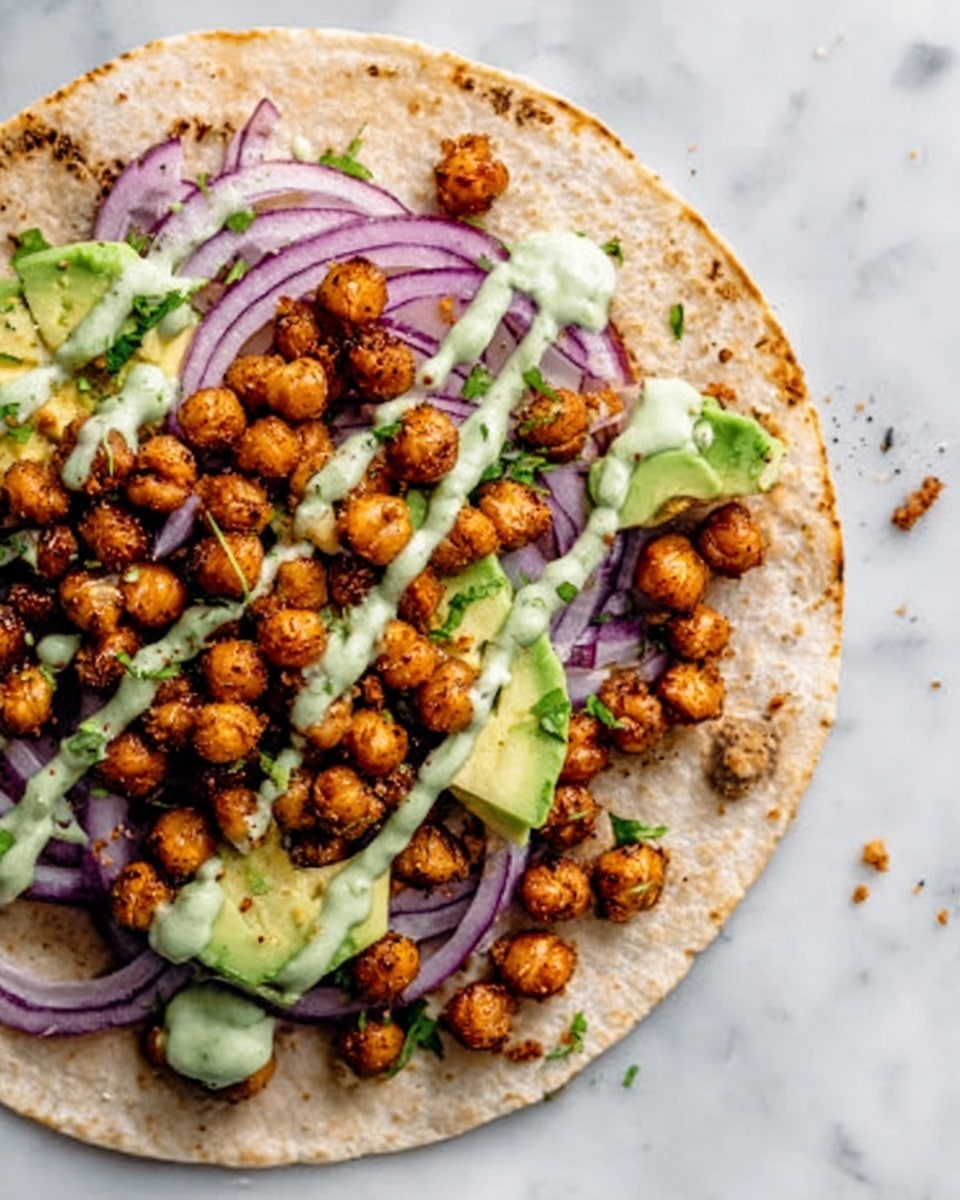 The image shows a white tortilla flat on a white marbled surface with a mix of crispy roasted chickpeas, bright green slices of avocado, and light green creamy sauce drizzled on top. Underneath this, there are thin purple slices of onion spread across the tortilla. The layers create a colorful, fresh look with the golden brown chickpeas adding texture and crunch, all presented in a casual, inviting way. Photo taken with an iphone --ar 4:5 --v 7