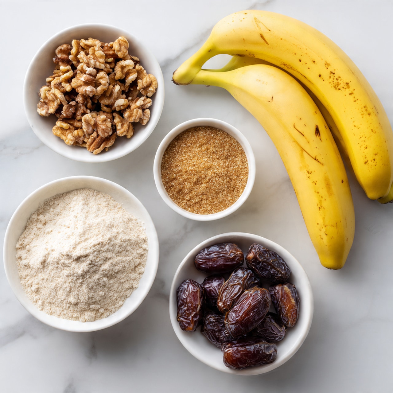 The image shows several white small bowls with different ingredients placed on a white marbled surface. One bowl contains dark brown, rough-textured walnuts, another has light tan brown sugar grains, a third bowl holds smooth off-white flour, and a fourth bowl is filled with dark, shiny dates. Next to these bowls are three yellow bananas with small brown spots on their skin. The bowls and bananas are arranged neatly with a white background. photo taken with an iphone --ar 4:5 --v 7