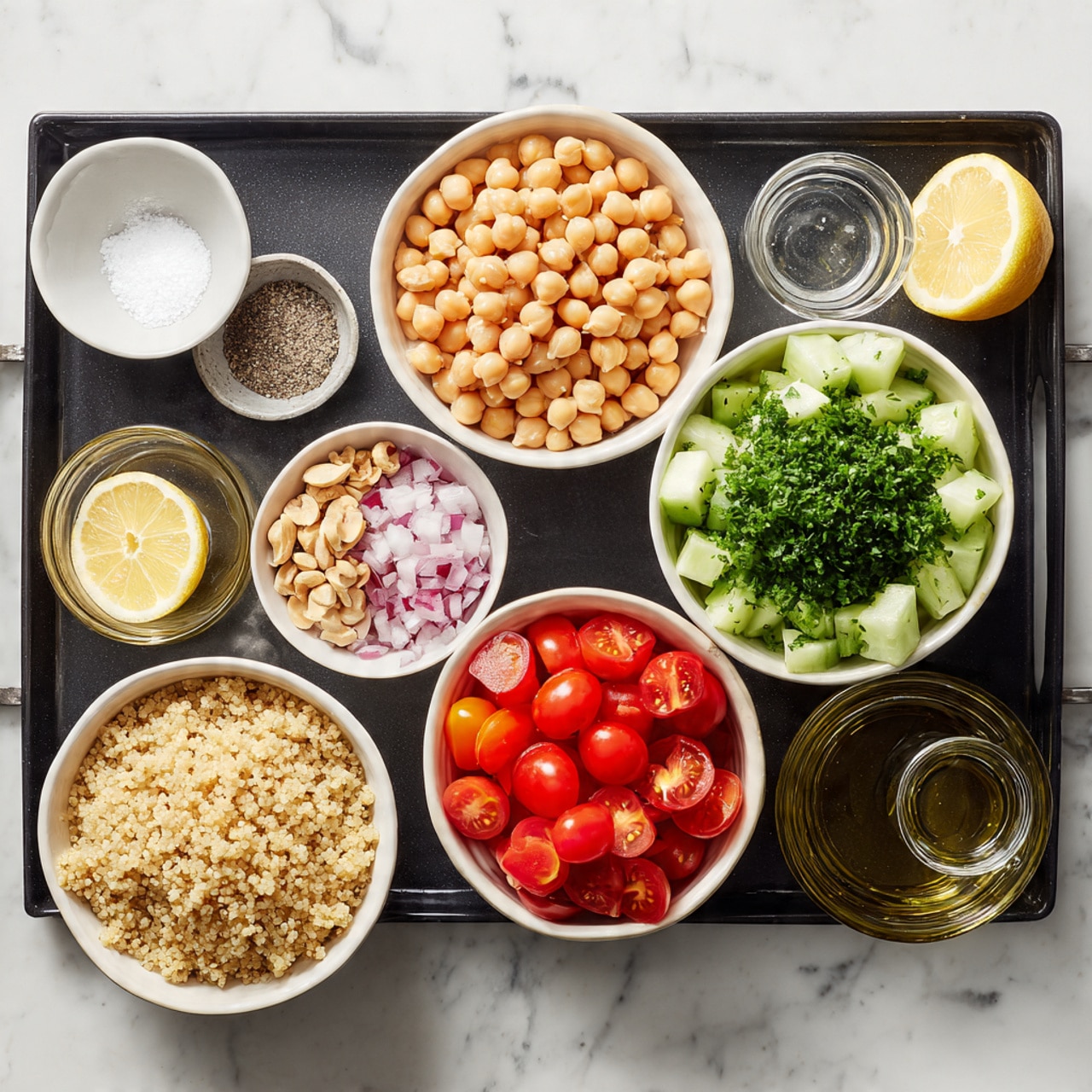 A black tray is placed on a white marbled surface, holding several white bowls filled with ingredients arranged neatly. In the top left is a small white bowl with salt and pepper, next to a larger bowl filled with round, light brown chickpeas. To the right of that is a medium bowl with chopped cucumber pieces, and below the chickpeas a large bowl full of bright green chopped parsley. Next to the parsley, a smaller bowl contains halved cherry tomatoes showing their red and slightly orange insides. Moving down, a bowl of cooked quinoa with a fluffy texture and beige color sits near red chopped onions in a small bowl. Around the edges of the tray are three small clear glass containers, one with minced garlic, one with a golden liquid likely oil, and the last with a few light brown nuts or seeds. A halved lemon rests near the glass containers. The overall setup is clean and organized, with fresh colors contrasting against the white bowls and marbled surface photo taken with an iphone --ar 4:5 --v 7