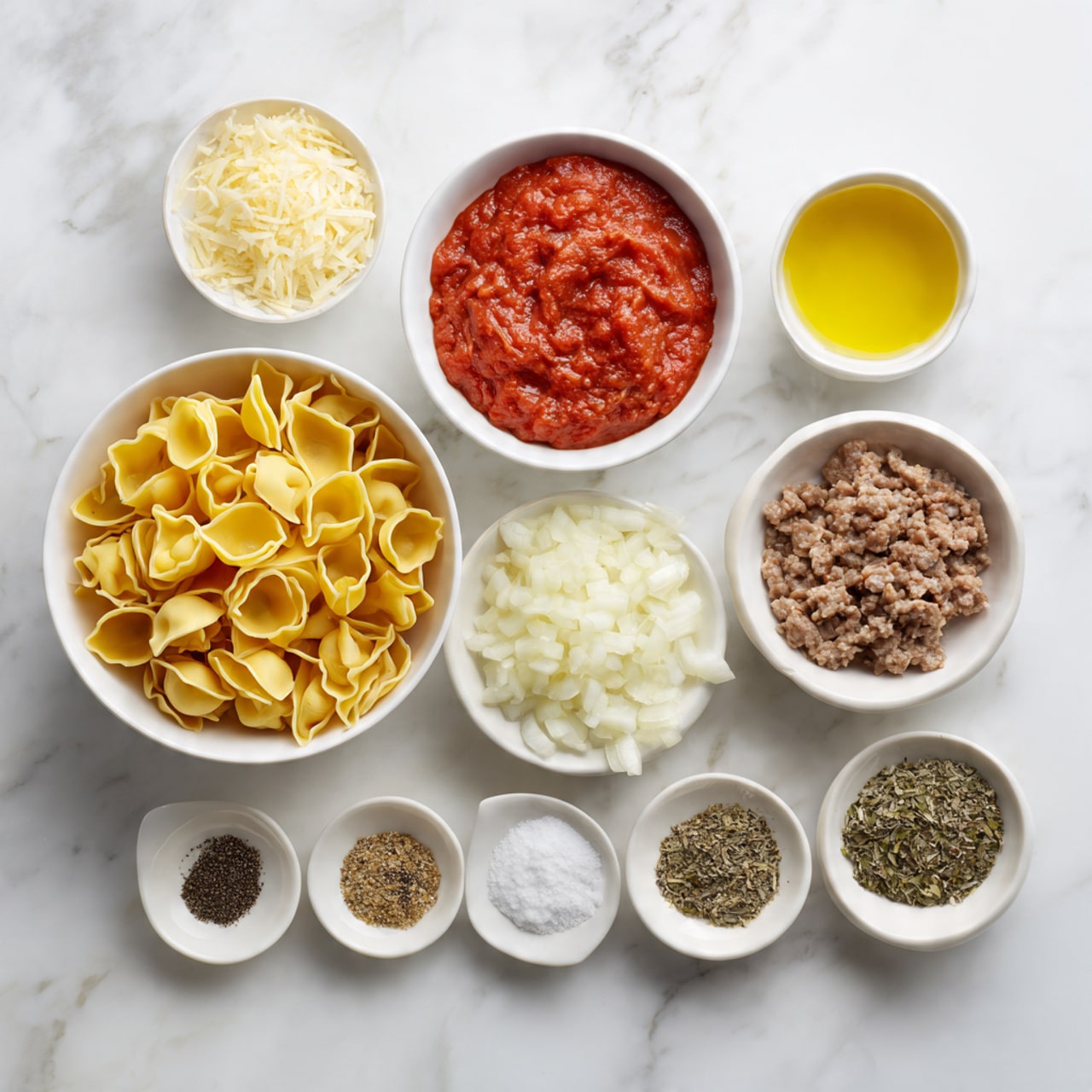The image shows bowls and small dishes arranged on a white marbled surface, each containing different ingredients for cooking. There is a large white bowl filled with yellow cooked pasta tubes, and another large white bowl with bright red tomato sauce. Smaller white bowls hold finely chopped white onions, minced garlic pieces, cooked ground meat, grated pale yellow cheese, and a light yellow liquid, likely oil. There are also tiny white bowls with black pepper, salt, and dried green herbs. The arrangement is neat and the colors range from red, yellow, and white to brown and green, creating a colorful and fresh look. Photo taken with an iphone --ar 4:5 --v 7