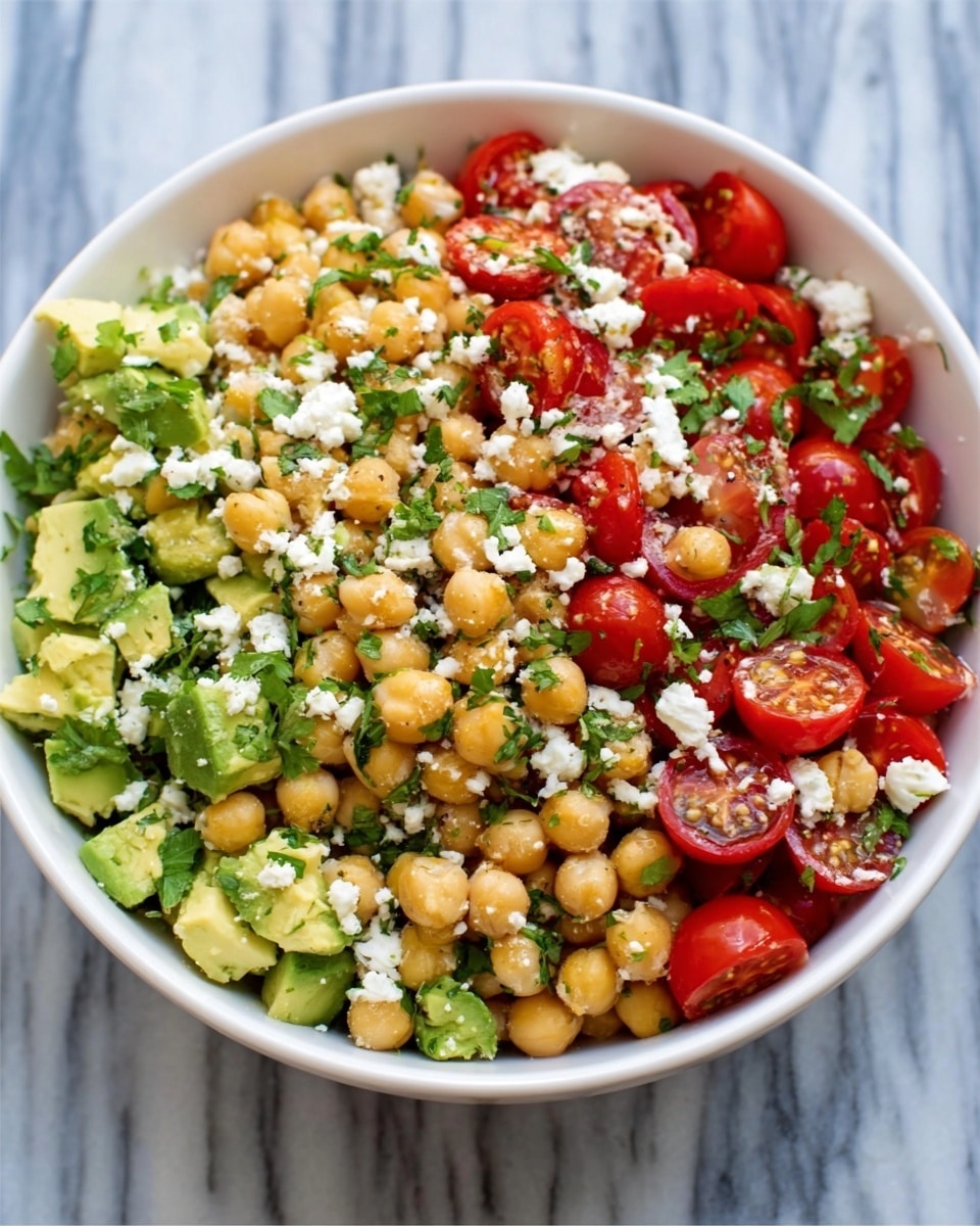 The image shows a white marble surface with an arrangement of small clear glass bowls and containers holding different ingredients neatly placed in rows. From the top left, there are two black-top jars, a small clear bottle of oil, a bowl filled with beige chickpeas, and half a lemon with its yellow inside facing up. Below them are a bowl of red cherry tomatoes, a bowl of finely chopped red onions, and a bowl of light green parsley. Further down, a half red onion, a bowl of white cheese cubes, and a bowl of diced avocado sit near a whole dark green avocado. The colors are vivid and fresh, with reds, greens, whites, and yellows contrasting against the white marble background. Photo taken with an iphone --ar 4:5 --v 7