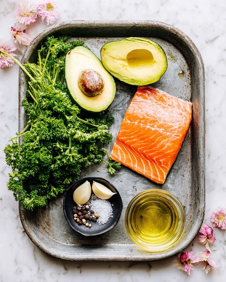 A rustic metal tray holds a bright orange piece of raw salmon on the upper right, with clear visible texture and lines; to the upper left, a halved avocado with one half showing the large brown seed and the other empty, both with smooth greenish-yellow flesh; a bunch of fresh green curly parsley sits below the avocado, spreading out toward the tray's bottom left; three light beige garlic cloves rest below the parsley, near the tray's center; a small black bowl on the right side contains coarse salt and whole black peppercorns; and below the bowl, a clear glass container is filled with golden oil, all set on a white marbled surface with soft pink and white flower buds scattered lightly around the ingredients photo taken with an iphone --ar 4:5 --v 7