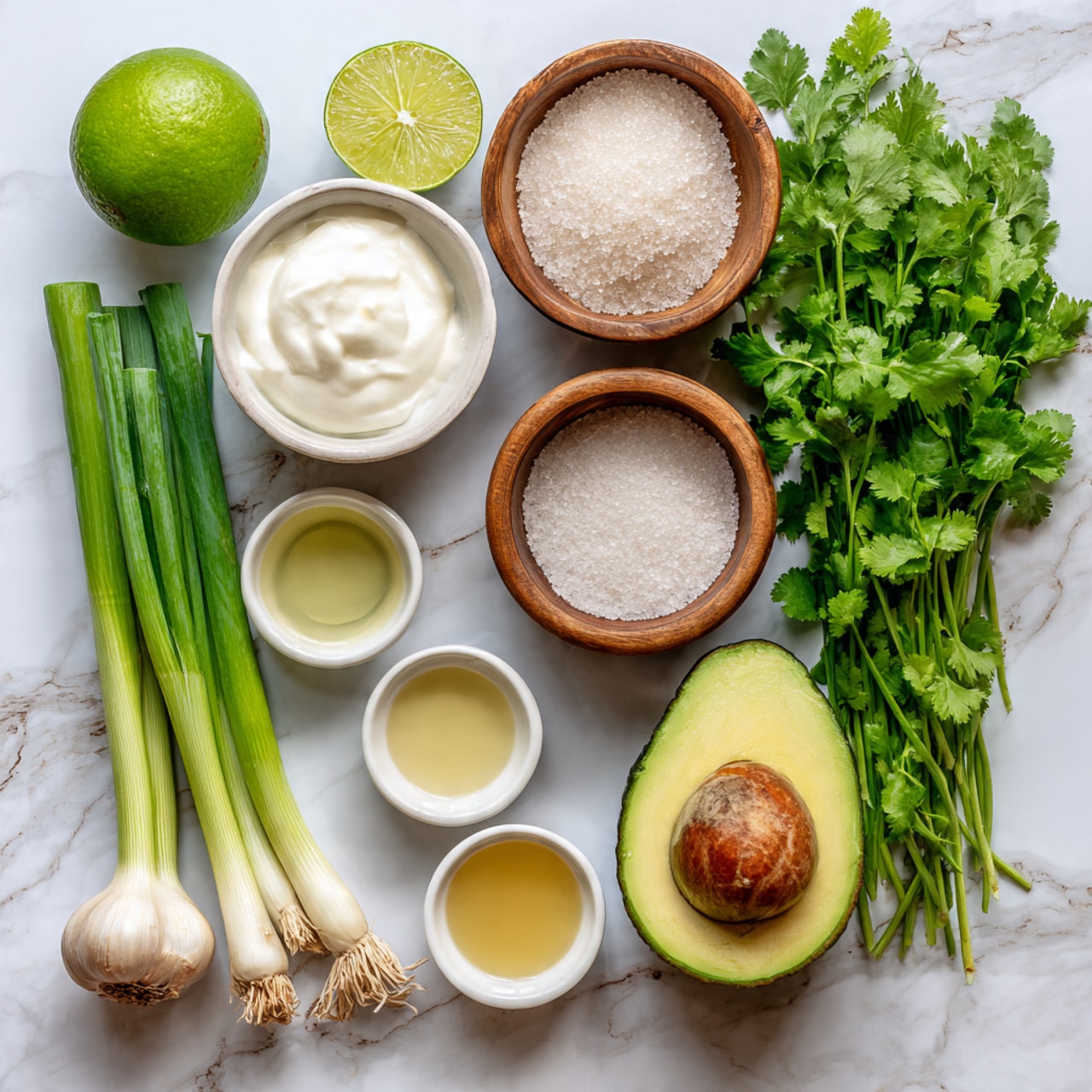 The image shows fresh ingredients neatly arranged on a white marbled surface. There is a whole lime on the top left, a small white bowl of thick white yogurt above the center, and a wooden bowl filled with coarse salt on the top right. Below the lime, three fresh green onions lie side by side with their white roots at the bottom. Near the center right, a bunch of fresh green cilantro fills a large area, next to a halved avocado showing its smooth green flesh and brown seed. At the bottom left, a whole garlic bulb with unplugged cloves sits next to four small white bowls containing light golden and clear liquids, scattered in the spaces around the green onions and cilantro. The whole scene is clean and bright with simple natural colors. Photo taken with an iphone --ar 4:5 --v 7