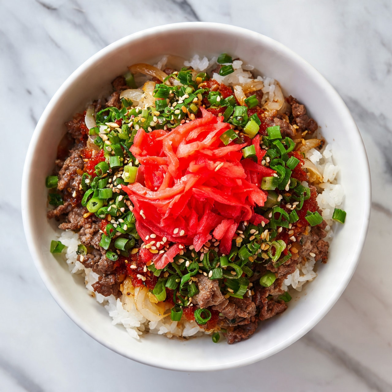 A white bowl on a white marbled surface holds a dish with three main layers. The bottom layer is white rice, barely visible under the toppings. The middle layer is thin slices of cooked brown beef mixed with soft, translucent cooked onions. The top layer is a bright red pile of thinly sliced pickled ginger placed in the center. The dish is sprinkled with chopped green onions and small pale yellow sesame seeds scattered evenly on top. Photo taken with an iphone --ar 4:5 --v 7