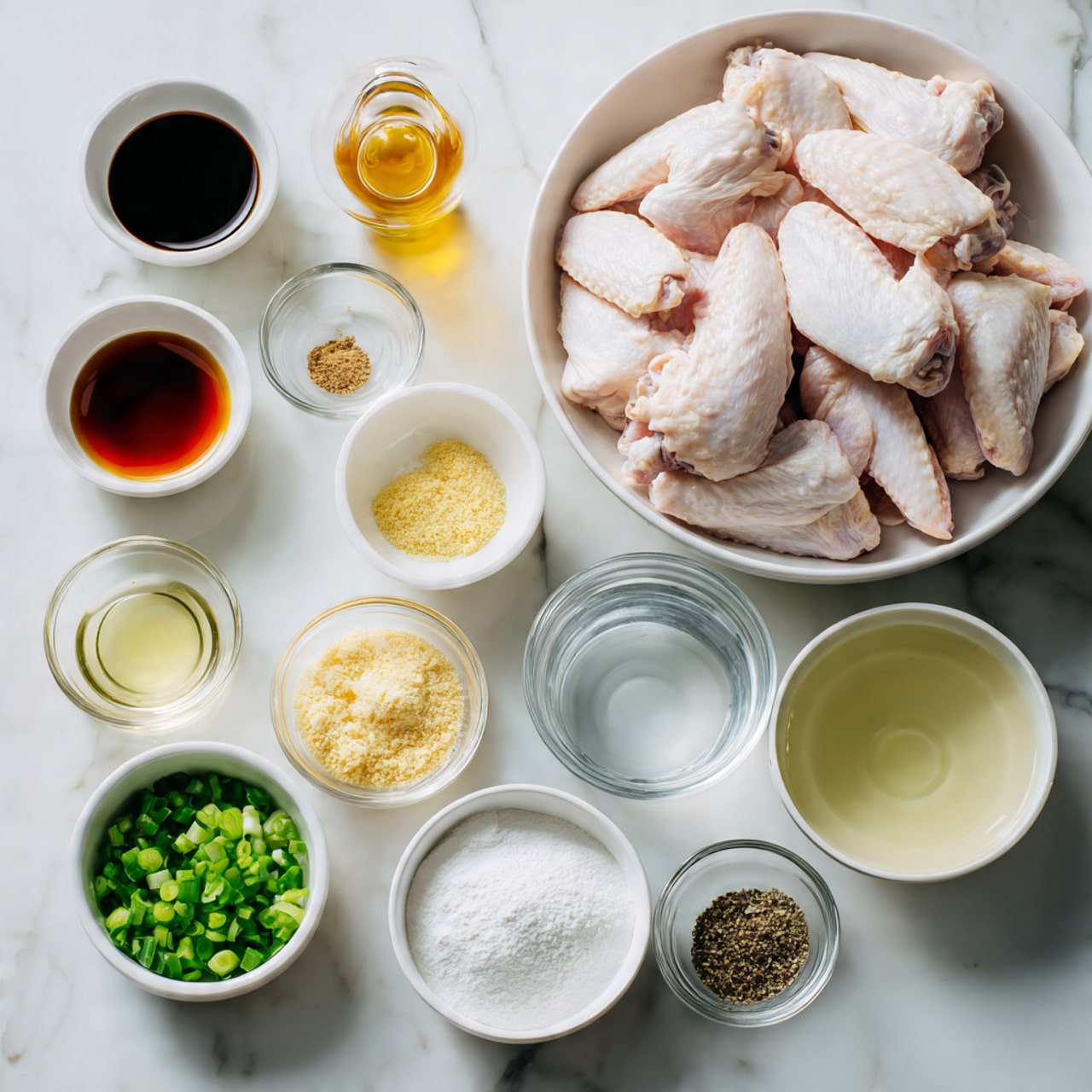 A large white bowl filled with many raw chicken wings, pale pink with smooth skin, sits on a white marbled surface. Around it are ten small white bowls and clear glass bowls arranged neatly, each holding different ingredients: dark soy sauce with a glossy black surface, amber-colored honey shining under the light, finely minced light yellow garlic, bright green chopped scallions, a bowl of white cornstarch with a soft powdery texture, and a bowl of clear water. Smaller clear bowls contain pale yellow garlic powder, coarse white salt, and ground black pepper with a speckled texture. Two small glass bowls hold light golden and pale yellow liquids, possibly vinegar and oil. All bowls are simple and round, placed in tidy rows, creating a clean and organized cooking setup, photo taken with an iphone --ar 4:5 --v 7