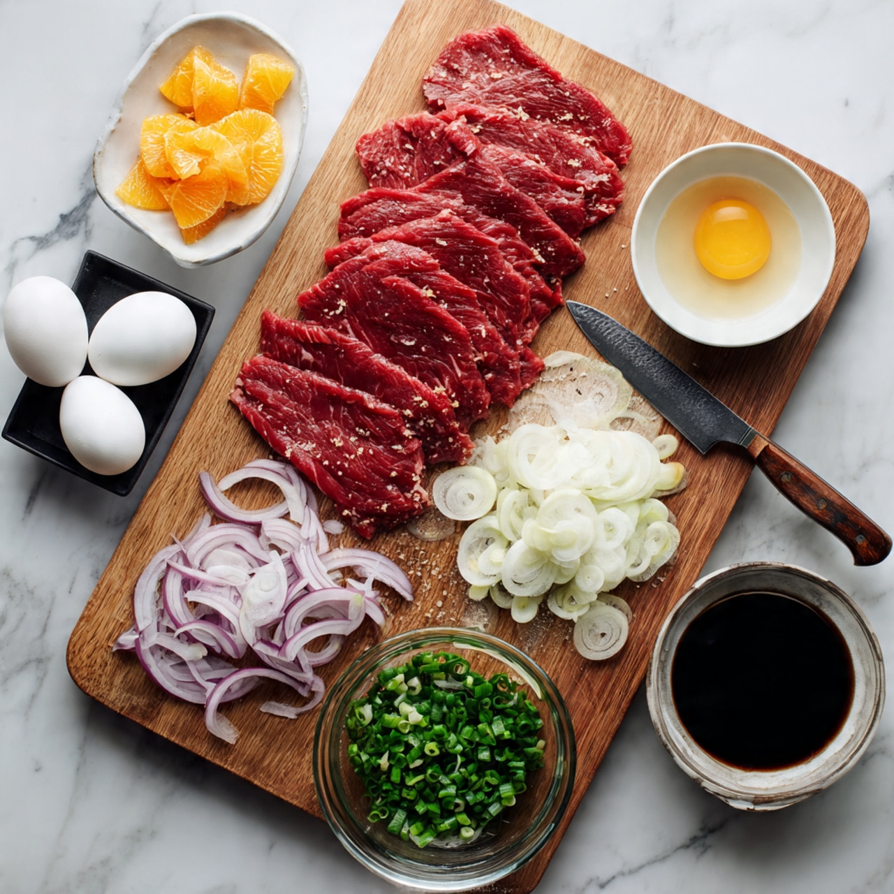 A wooden cutting board sits on a white marbled surface, holding five thin slices of raw red meat arranged side by side near the top left. To the top right of the meat is a small white bowl with a pale liquid inside. Next to the bowl is a whole yellow onion. Below the onion and bowl, thinly sliced rounds of white and purple shallots mix with chopped green onions. A large knife with a wooden handle rests on the cutting board near the chopped vegetables, with bits of green onion on the blade. Below the meat, a clear glass bowl contains a dark soy-like liquid. To the bottom left of the board, two white eggs sit on the marbled surface next to a small black tray with thin slices of bright orange pickled ginger. Off to the top left corner, the edge of a glass bowl with a light brown sauce is visible, along with a scoop of white rice and a pinch of white salt on the marbled surface. Photo taken with an iphone --ar 4:5 --v 7