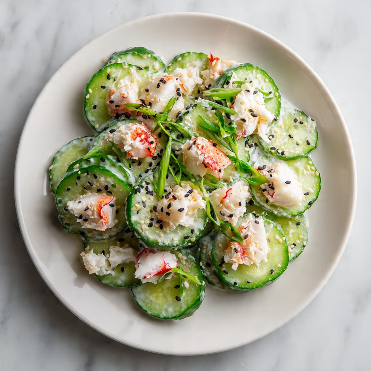 A white plate holds a layered cucumber salad with thin, round slices of cucumber making up the base layer, showing their bright green skin and light green centers. Scattered on top are small cubes of imitation crab meat, featuring white and red colors, mixed with a creamy dressing giving a slightly shiny texture. Thin chopped green onions add small bright green bits across the surface. Black sesame seeds are sprinkled evenly over the salad, contrasting sharply with the green cucumbers and creamy dressing. The plate is set on a white marbled surface. photo taken with an iphone --ar 4:5 --v 7