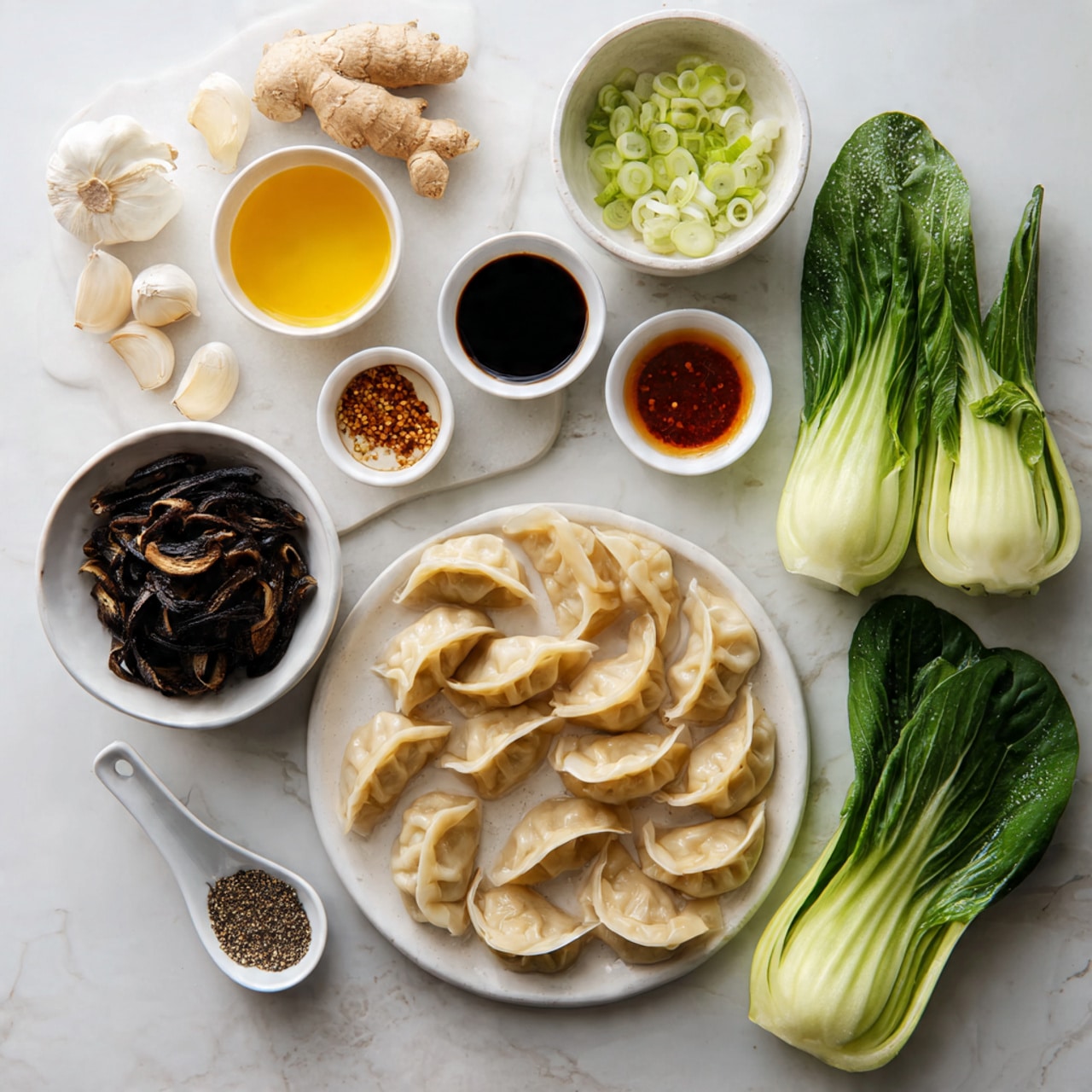The image shows arranged ingredients on a white marbled surface. At the center right, there is a white plate filled with about 15 light beige dumplings, showing slight browning and folded edges. Next to the plate, on the far right, are two fresh, green heads of bok choy with visible water droplets on the leaves. To the lower left of the dumplings, a white bowl contains dark brown dried shiitake mushrooms with wrinkled texture. Above this bowl is a small white container holding golden yellow liquid sauce. Toward the top left, a white round plate holds fresh ginger root, three peeled garlic cloves, and three small bowls with different sauces: a dark brown soy sauce, a golden oily sauce speckled with black pepper, and a reddish-brown sauce in a small white bowl. Near the top center is a small white bowl filled with sliced green onions, showing white and green rings. A white spoon with black pepper rests near the top left. photo taken with an iphone --ar 4:5 --v 7