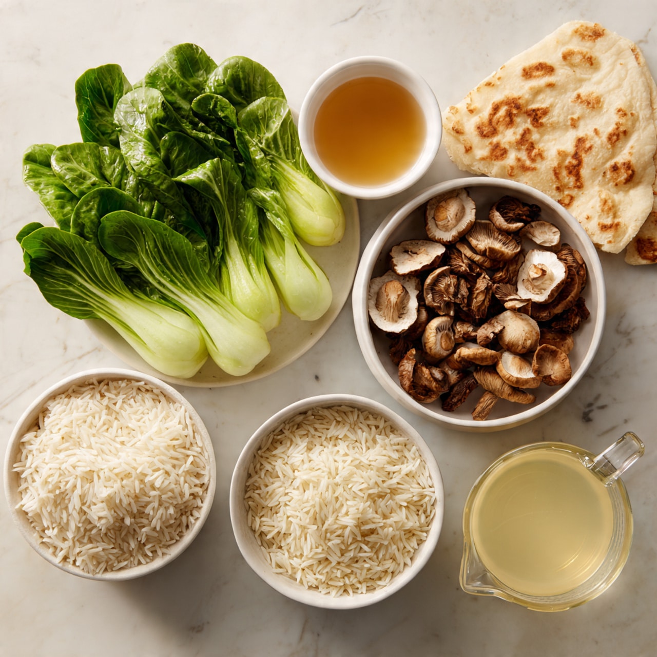 The image shows several small white bowls and a clear measuring cup arranged on a white marbled surface. The top left has bright green bok choy leaves with white stalks. To the right of the bok choy is a white bowl filled with brown and beige shiitake mushrooms, some whole and some sliced. Below the mushrooms is a white bowl with light brown liquid, and to its left is a large white bowl full of white rice grains. Next to it is a smaller bowl with more white rice grains. The large clear measuring cup at the right holds a light yellow broth or liquid. A piece of light brown flatbread rests near the bowl of mushrooms. photo taken with an iphone --ar 4:5 --v 7