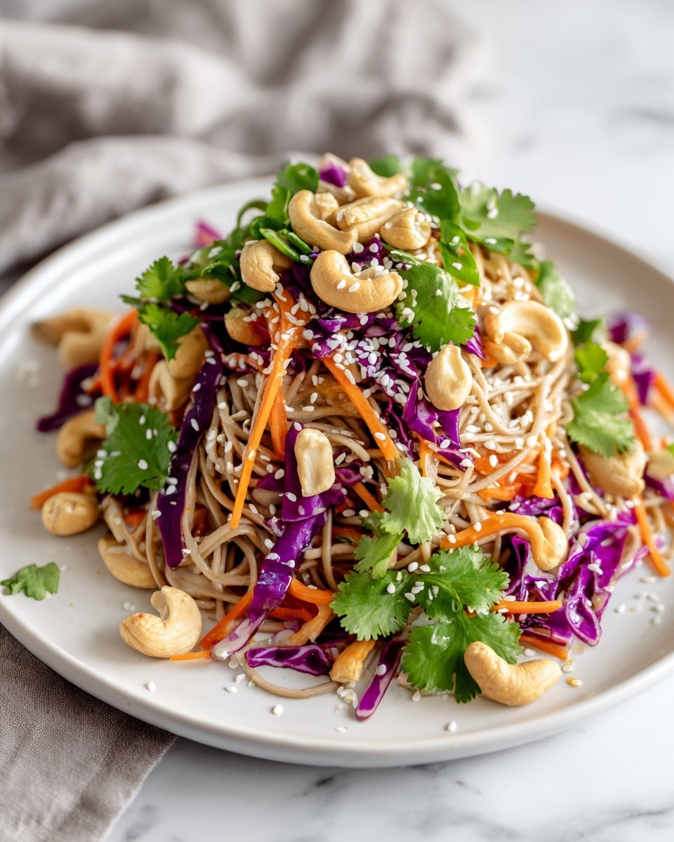 The image shows a white plate filled with a layered salad. The base layer consists of thin, light brown noodles spread evenly across the plate. On top of the noodles, there are thin strips of purple cabbage and shredded orange carrots scattered around. Bright green cilantro leaves are spread throughout the salad. White sesame seeds are sprinkled generously over the entire dish. Large light tan cashew nuts are scattered on top, adding texture. The plate is set on a white marbled background. photo taken with an iphone --ar 4:5 --v 7