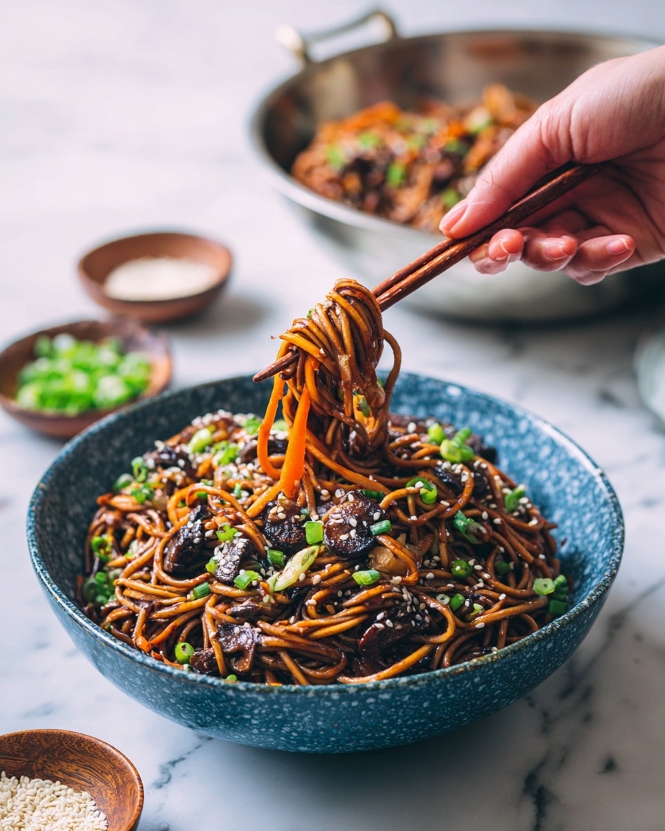 A blue speckled bowl filled with three layers of dark brown, glossy noodles mixed with thin orange carrot strips and small dark mushroom pieces. Light green chopped scallions and white sesame seeds are scattered on top of the noodles. A woman's hand using brown wooden chopsticks is lifting a small bundle of noodles and a carrot strip from the bowl. In the background is a metal bowl with more noodles. The surface beneath is a white marbled texture. Small wooden bowls with chopped green onions and white sesame seeds sit partially in view. Photo taken with an iphone --ar 4:5 --v 7
