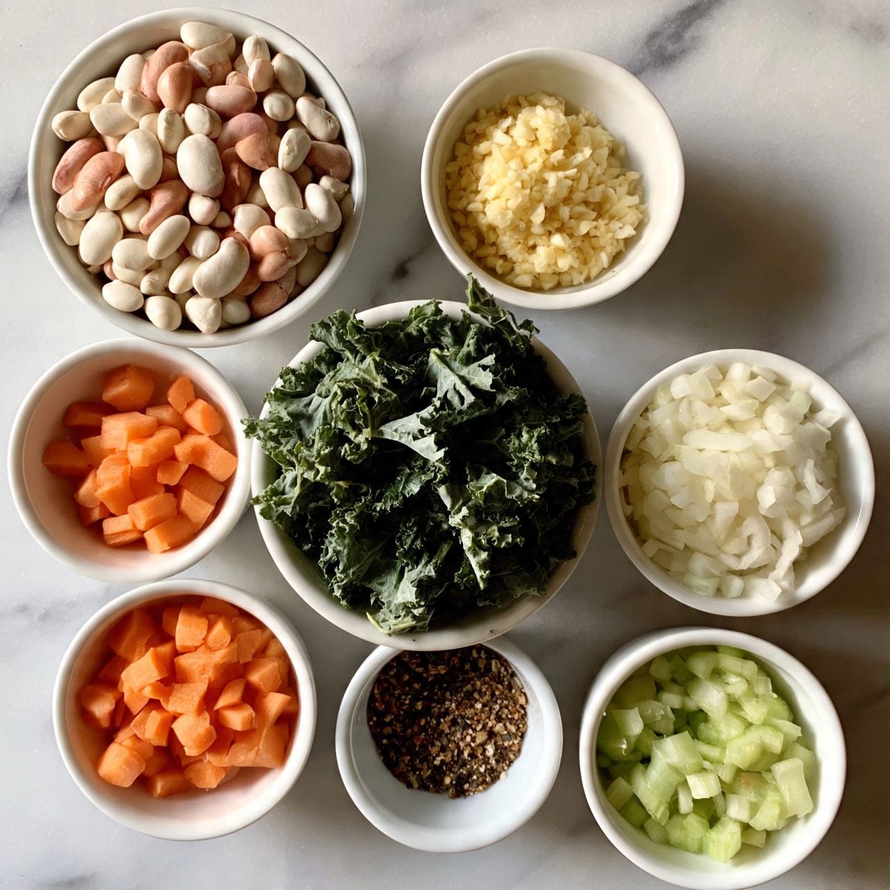 square image The image shows seven small white bowls arranged on a white marbled surface. The top left bowl is filled with white and pink beans. To its right, there is a small white bowl containing light yellow finely chopped garlic. Below the beans, a white bowl has small orange carrot pieces. In the center, a white bowl holds a large pile of dark green kale leaves. Next to the carrots, another white bowl contains chopped white onion. On the bottom right, a white bowl has small pieces of light green celery. Finally, between the onion and celery bowls, there is a small white bowl filled with a mix of brown and black spices. photo taken with an iphone --ar 4:5 --v 7