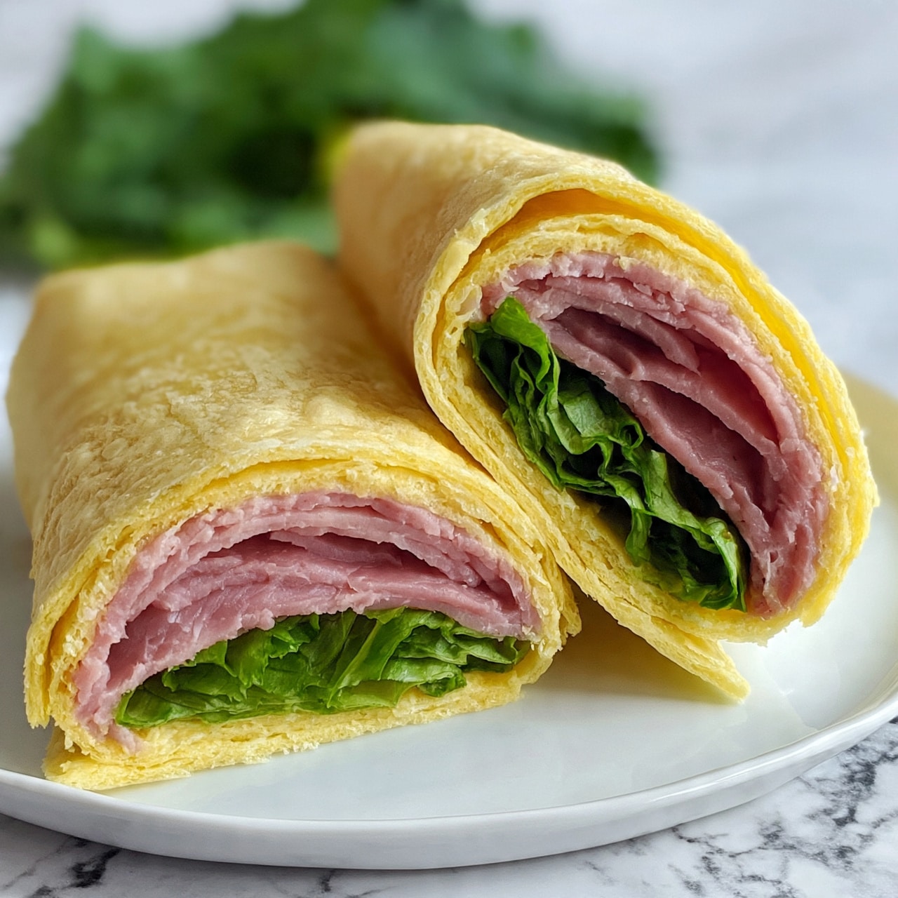 square image A close-up view of a wrap sandwich cut in half and placed side by side on a white plate. The wrap has a soft yellow tortilla as the outer layer. Inside, there is a layer of thinly sliced pink meat, followed by a fresh green layer of leafy lettuce. The wrap halves sit on a white marbled surface, with a green leafy vegetable blurred in the background. The wrap edges are slightly textured, showing the softness of the tortilla. photo taken with an iphone --ar 4:5 --v 7