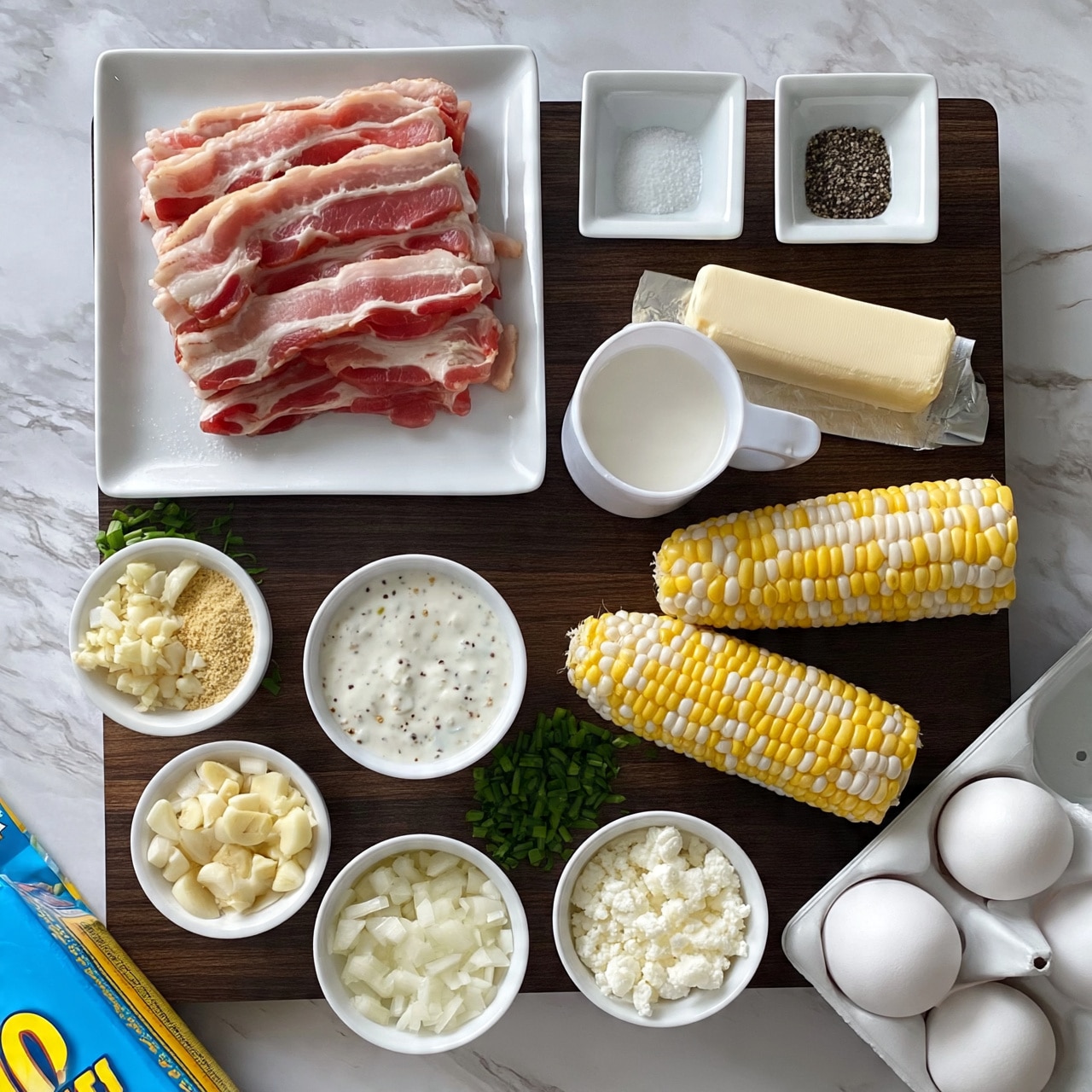 square image The image shows several cooking ingredients neatly arranged on a dark wooden surface. At the top left, there are slices of raw bacon on a white square plate. To the right of the bacon, two small white square dishes hold salt and black pepper. Below the bacon, there is a white measuring cup filled with milk, next to a stick of butter wrapped in paper. Below these, a small white bowl has a creamy white sauce with specks of herbs. On the lower right side, two ears of yellow and white corn rest on the surface. Below the corn, chopped green chives are in a small white bowl. Other small white bowls hold minced garlic, garlic powder, chopped onions, and white crumbly cheese. At the bottom right corner, there is a white egg carton with three white eggs inside. A blue and yellow box of corn muffin mix is at the left bottom edge. The background should appear as white marbled texture. photo taken with an iphone --ar 4:5 --v 7