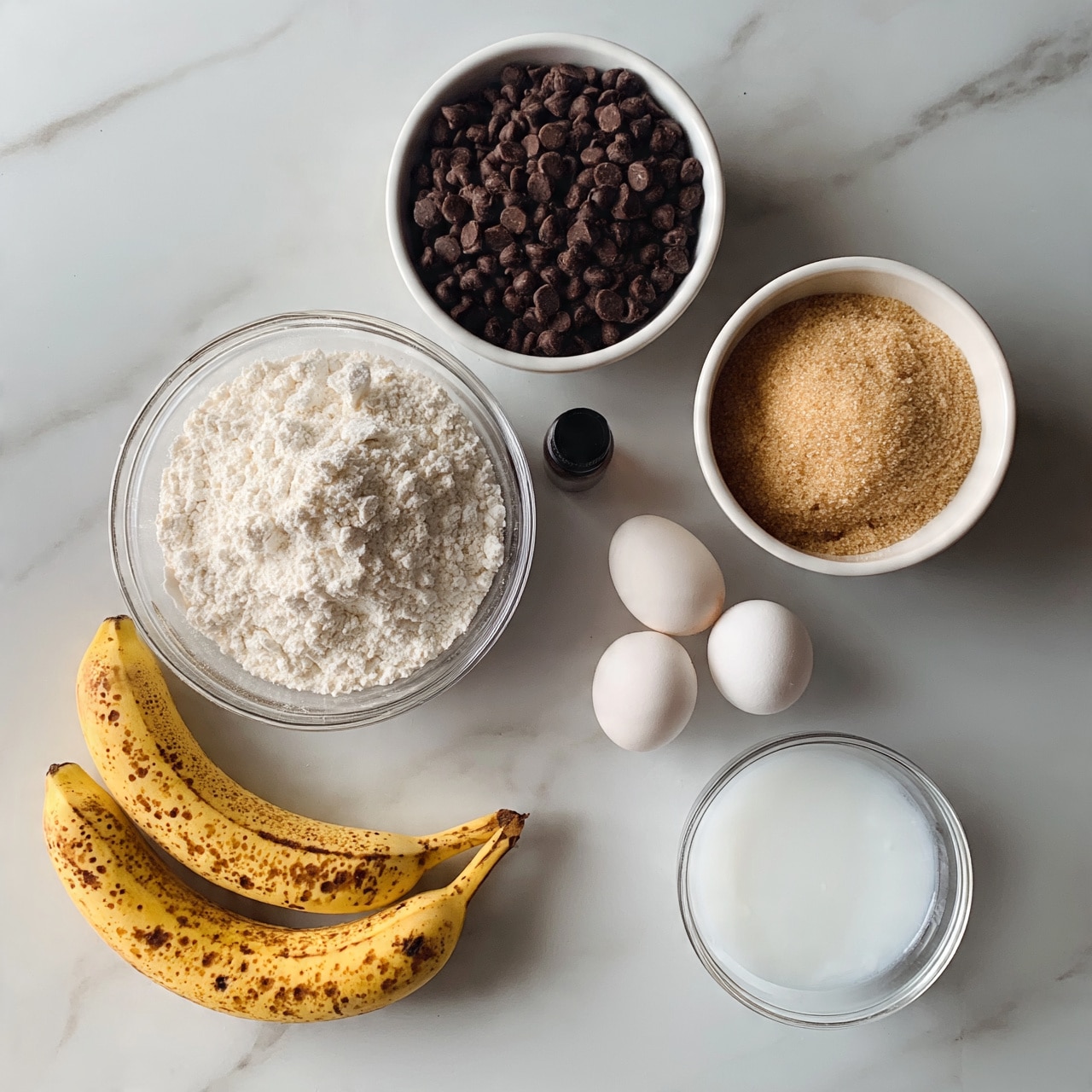square imageThe image shows ingredients for baking arranged neatly on a white marbled surface. There are seven items visible: two ripe bananas with brown spots at the bottom left, a clear glass bowl full of white flour at the middle left, a white bowl filled with small dark chocolate chips at the top center, another white bowl with light brown sugar at the right middle, two white eggs placed next to each other near the center right, a small clear glass bowl containing white liquid (likely coconut oil or milk) at the bottom right, and a small dark bottle of vanilla extract between the flour bowl and eggs. The colors are soft and natural, showing textures like powdery flour, smooth eggs, and the rough surface of bananas. photo taken with an iphone --ar 4:5 --v 7