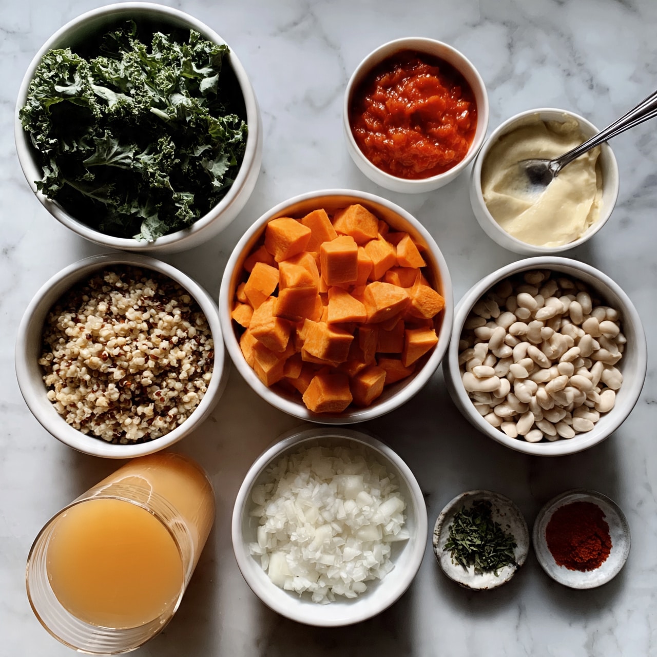 square image The image shows a white bowl filled with green leafy kale in the top left. To the right of it is a small white bowl with red tomato sauce, and next to that is a small white bowl with a creamy light yellow substance, with a silver spoon resting inside. Below these bowls, there is a white bowl filled with orange cubed sweet potatoes in the center. To its left is a white bowl of mixed grains, possibly quinoa, and to the right is a white bowl filled with white beans. Below, there is a glass of light orange juice on the left, a white bowl of finely chopped white onions in the center, and on the right two small dishes: one with green herbs and the other with a red spice. All items are on a white marbled surface. photo taken with an iphone --ar 4:5 --v 7