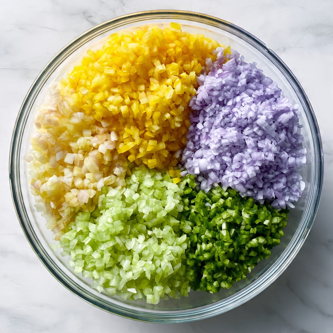 square image A clear glass bowl sits on a white marbled surface, filled with five colorful layers of diced vegetables arranged separately in a circular pattern. Starting from the top, there is a bright yellow layer of small diced pieces, followed by a light purple layer of finely chopped pieces to the right. At the bottom right, there is a layer of small green diced pieces. Next, at the bottom left, there is a layer of light green chopped pieces, and finally, on the left side, a layer of pale whitish-yellow diced pieces. The textures vary from smooth to slightly rough for each vegetable. photo taken with an iphone --ar 4:5 --v 7
