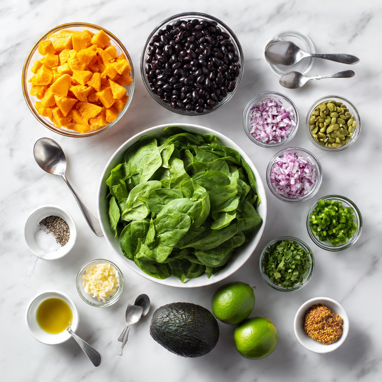 square image The image shows various fresh ingredients arranged neatly on a white marbled surface. In the center, there is a white bowl filled with bright green spinach leaves. Above it to the left, a glass bowl holds chunky, bright orange sweet potato pieces. Next to that, a bowl contains shiny black beans. To the right of the spinach, small glass bowls contain finely chopped red onions and green pumpkin seeds. Below, near the bottom center, there is a whole dark green avocado and two limes. Several small white and metal bowls and spoons hold olive oil, salt and pepper, chopped cilantro, chopped green peppers, minced garlic, and grainy mustard, spaced evenly around the main bowls. photo taken with an iphone --ar 4:5 --v 7