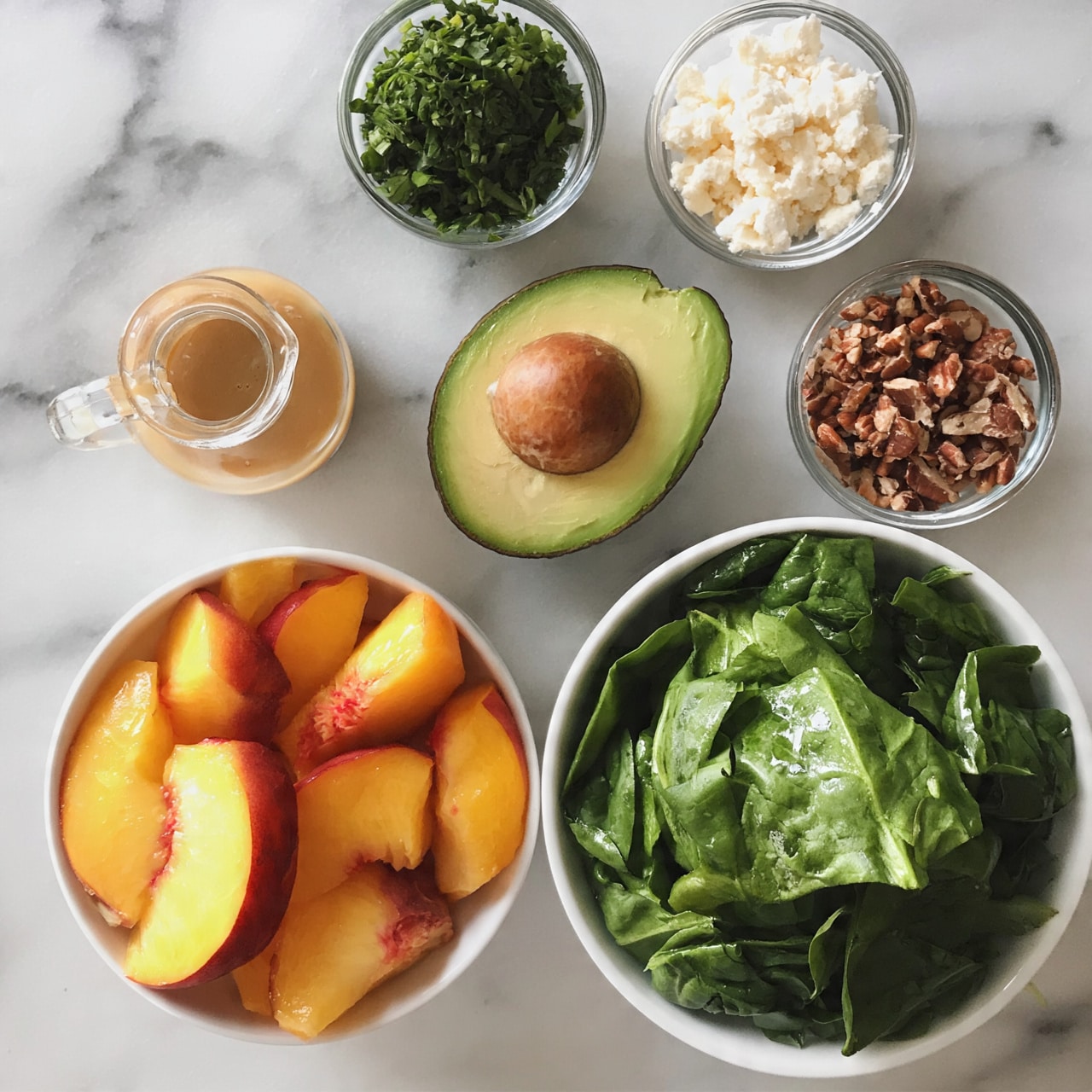 square image The image shows several ingredients neatly arranged on a white marbled surface. In the bottom right, there is a white bowl filled with fresh green spinach leaves, folded and slightly shiny. To its left, another white bowl contains sliced peach pieces with bright orange and red skins and juicy yellow flesh. Above these bowls, there is a halved avocado showing smooth, light green flesh and one half with a large brown pit. Surrounding the avocado, four small clear glass bowls hold different ingredients: chopped green herbs in the top center, crumbled white cheese slightly to the right, chopped pecans on the far right, and a light brown dressing in a small glass jug to the far left. The overall setup is clean and organized, with fresh colors and natural textures. Photo taken with an iphone --ar 4:5 --v 7