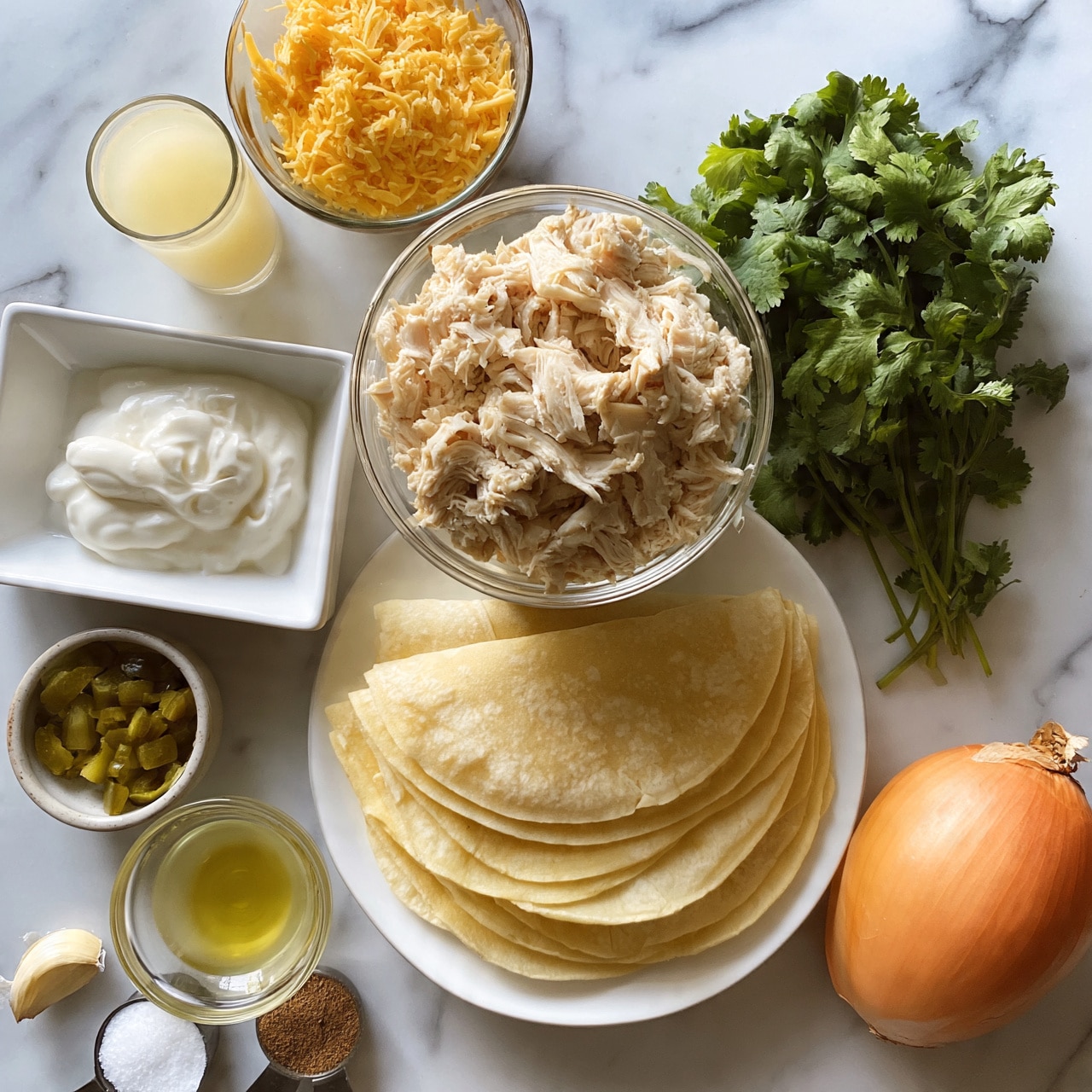 square image The image shows a white marbled surface with various ingredients neatly arranged. In the center, there is a clear glass bowl filled with shredded cooked chicken. Below it, several stacked pale yellow tortillas are placed on a white plate. To the upper left of the chicken, there is a bowl filled with golden shredded cheese, next to a small glass of light yellow sauce or juice. To the left of the tortillas, there is a rectangular white dish with white sour cream, and nearby, a small bowl with chopped green pickles. To the right of the chicken, there is a bunch of fresh green cilantro. On the bottom left, there is a half garlic clove, a small clear bowl with yellow oil, and measuring spoons holding white salt and a brown spice. On the bottom right, there is a whole orange onion. Everything is placed on a white marbled surface. Photo taken with an iphone --ar 4:5 --v 7