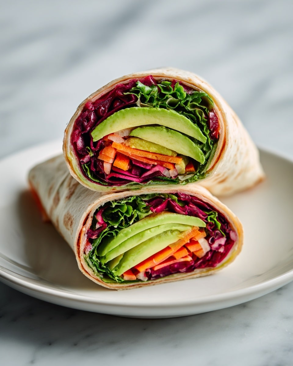 The image shows a white plate on a white marbled surface holding a wrap cut in half and stacked vertically. The wrap has multiple layers visible inside: the outer layer is a light brown tortilla, followed by a thick layer of dark green leafy lettuce at the bottom. Above the greens are thin slices of red and orange vegetables, likely carrots and red cabbage, adding bright pops of color. At the top, slices of avocado with pale green flesh curve along the wrap edges. The overall look is fresh, crisp, and colorful with clear, distinct layers. Photo taken with an iphone --ar 4:5 --v 7