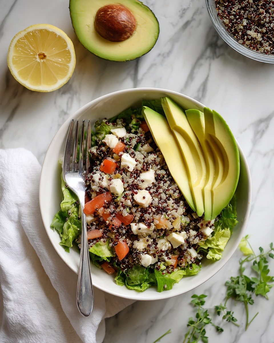 A white bowl filled with a quinoa salad made of three layers: the bottom layer is light green lettuce, the middle layer consists of a mix of white, red, and black quinoa grains with small chunks of white cheese, red tomatoes, and beige pieces of chicken, and the top layer shows three slices of smooth, yellow-green avocado resting on the salad's right side; a silver fork stands upright inside the bowl on the left. Around the bowl on a white marbled surface, there is half a lemon at the top left, an avocado half with its large brown seed below it, a glass bowl containing more of the salad at the top right partially on a folded white cloth, and a small green herb sprig near the center bottom edge. Photo taken with an iphone --ar 4:5 --v 7