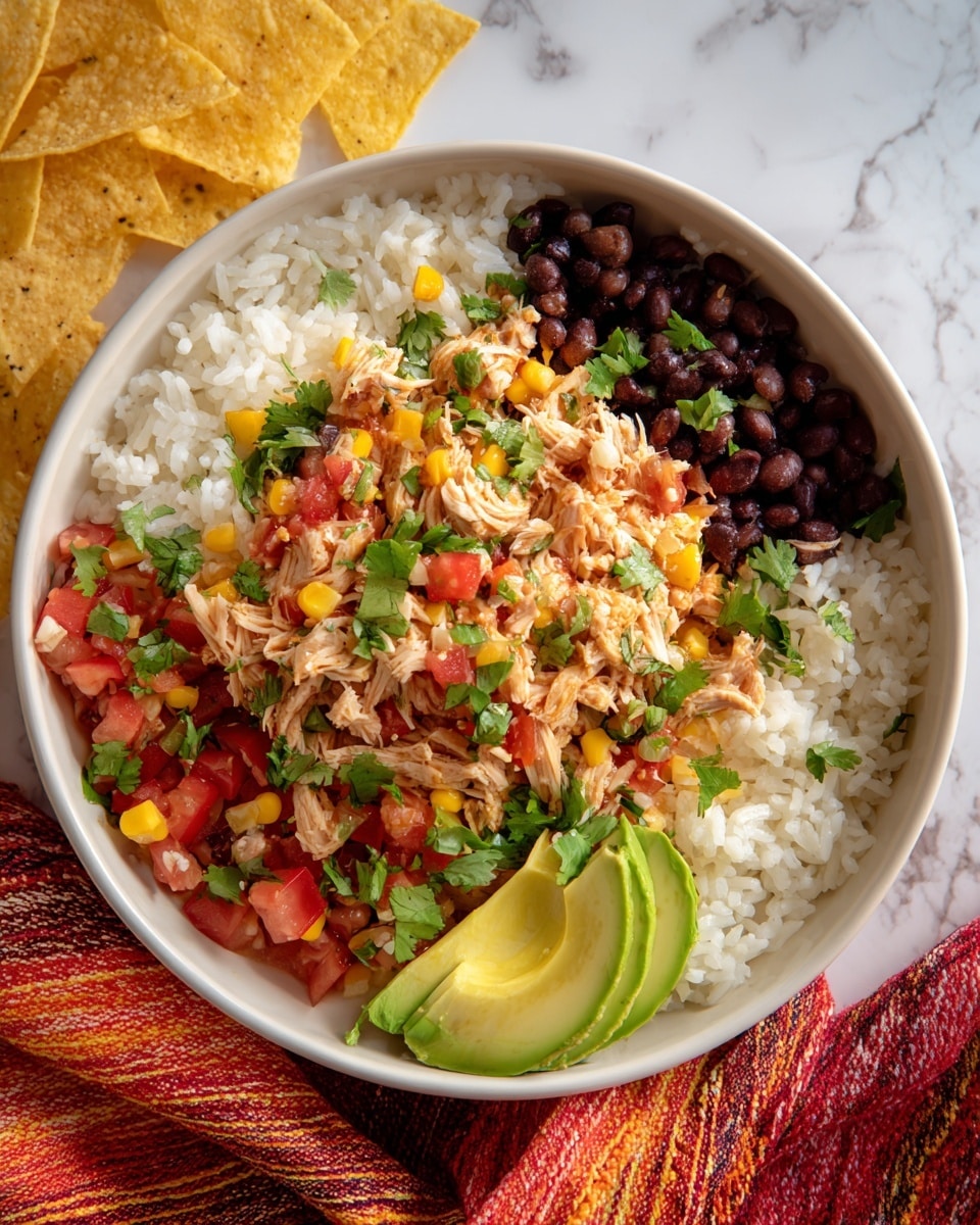 The image features a large white bowl filled with a colorful layered salad on a white marbled surface. The base layer is a generous amount of shredded light beige chicken mixed with white rice. Scattered throughout the salad are black beans, small diced red tomatoes, and bright green cilantro leaves, adding spots of black, red, and green colors. Alongside the bowl are light yellow tortilla chips and sliced light green avocado wedges. A woven red and orange cloth is partially visible near the bowl. The overall texture looks soft with some chunky and fresh elements mixed in, creating a vibrant and inviting dish. Photo taken with an iphone --ar 4:5 --v 7