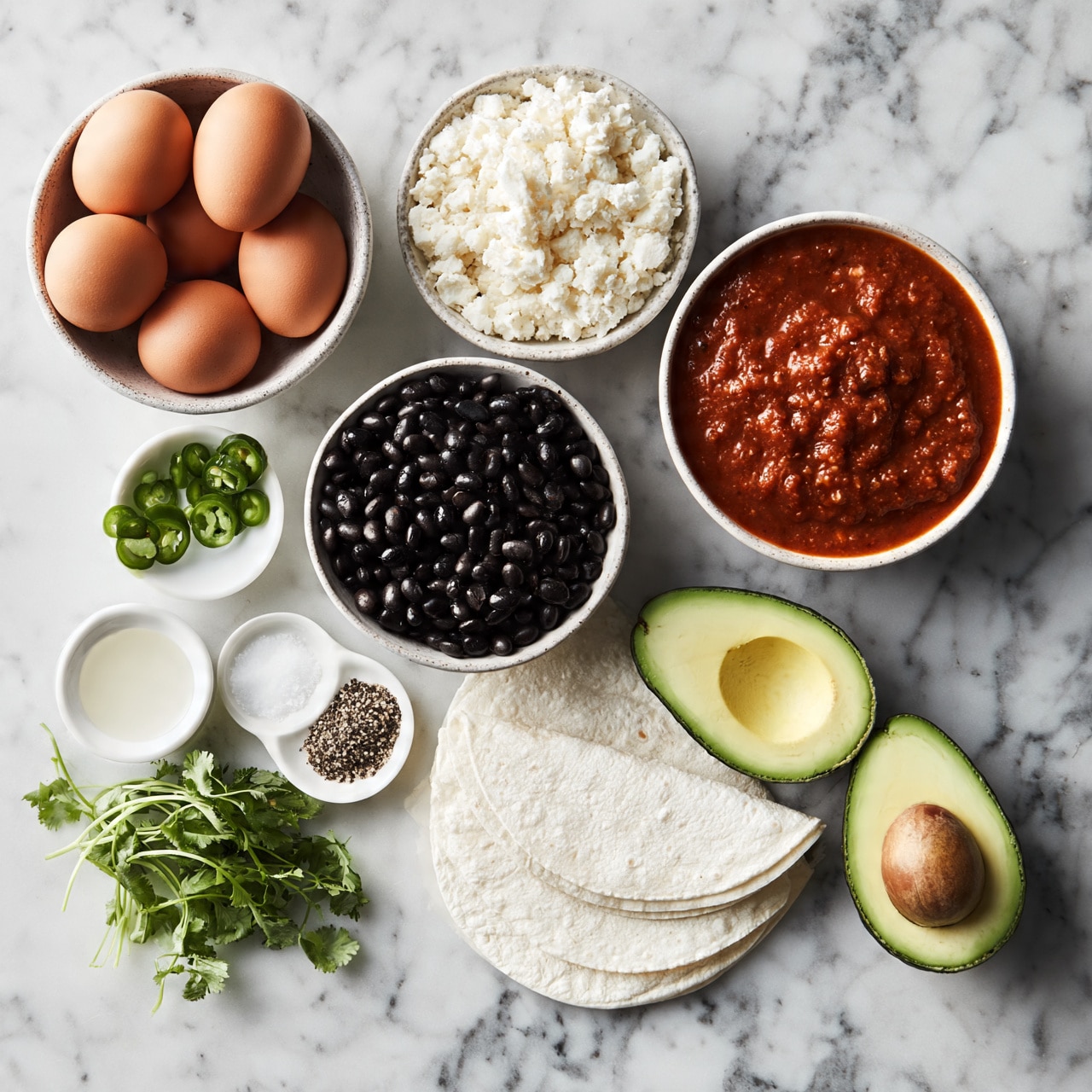 square image The image shows a flat lay of various fresh ingredients arranged neatly on a white marbled surface. There is a bowl of brown eggs, a bowl of white cheese with a crumbly texture, a bowl of black beans, and a bowl of red sauce with a smooth, slightly chunky texture. Next to them are small white bowls containing sliced green jalapeños, a clear liquid, salt, and black pepper, all placed around two white corn tortillas laid flat. Two halves of an avocado with a smooth green flesh and brown pit are near a small bunch of fresh green cilantro with thin stems. Photo taken with an iphone --ar 4:5 --v 7