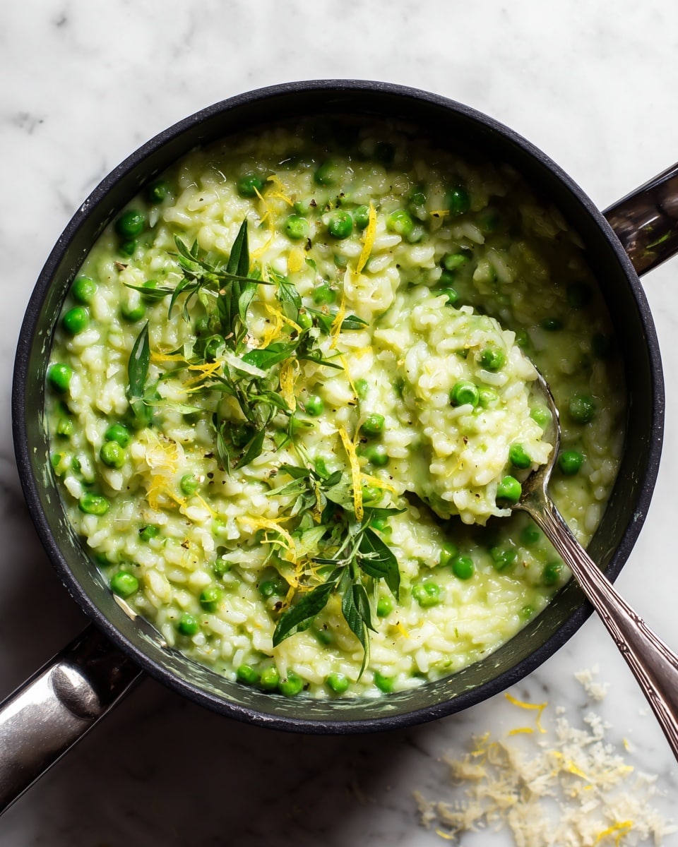 The image shows a black cooking pot filled with creamy green risotto mixed with bright green peas. The risotto has a thick, soft texture with visible grains of rice blended into a light green sauce. On top, there are small fresh green leaves and thin yellow lemon zest strips, adding detail and color contrast. A silver spoon inside the pot scoops up some risotto, revealing the mix of peas and rice. The pot sits on a white marbled surface with some scattered grated white cheese around it. photo taken with an iphone --ar 4:5 --v 7