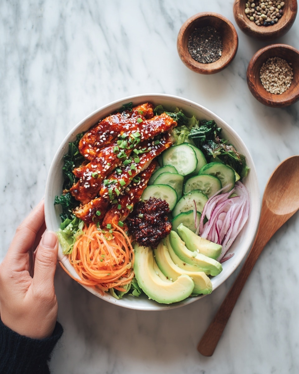 The image shows a white round bowl filled with a colorful meal placed on a white marbled surface. The bowl has three main layers: at the bottom, there are dark green leafy vegetables mixed with thin orange carrot strips. On top of this base, there are pieces of glazed grilled chicken with a shiny reddish-brown color, sprinkled with sesame seeds and small green herbs. On the right side, there are fresh slices of pale green avocado, light green cucumber, and bright yellow-green lettuce leaves. Near the avocado, there is a small mound of dark red sauce or paste. To the right, thin slices of red onion add a pop of purple color. A woman's hand is holding a wooden spoon next to the bowl. In the background, there are two small wooden bowls with seeds or spices. The photo was taken with an iphone --ar 4:5 --v 7