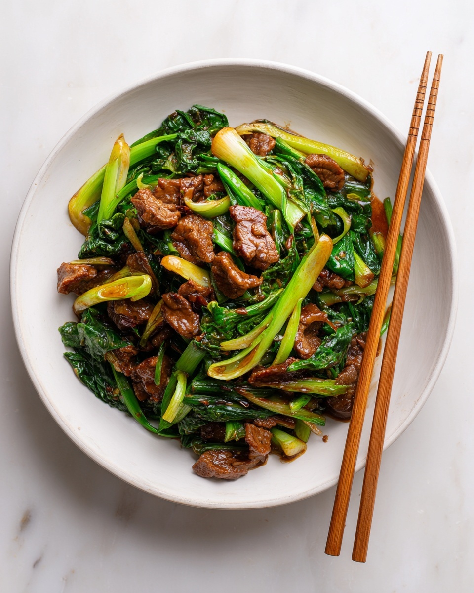 A white plate filled with a colorful stir-fry dish, featuring tender brown pieces of meat mixed with bright green vegetables like bok choy and scallions. The dish shows layers of meat and greens stirred together, with a glossy sauce coating all ingredients, creating a shiny and appetizing texture. A pair of wooden chopsticks rests on the edge of the plate, placed on a white marbled surface that adds a clean look to the image. photo taken with an iphone --ar 4:5 --v 7