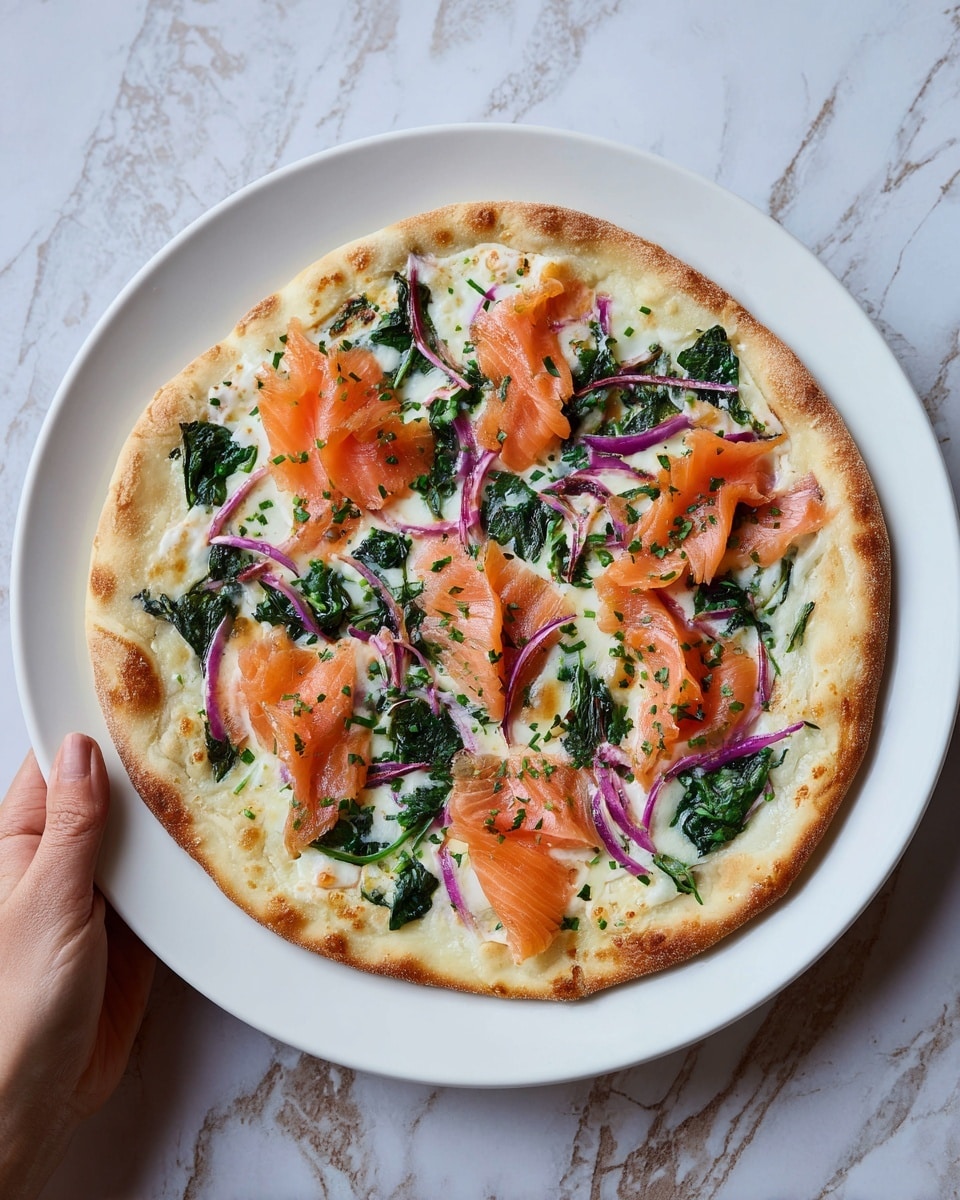 A round pizza with a thin, light golden crust sits on a white plate, topped with layers starting from a base of melted white cheese spread evenly. On top, there are bright orange slices of smoked salmon arranged in small folds, scattered pieces of cooked green spinach leaves, and thin rings of purple onion distributed across the pizza. Small sprinkles of green herbs are spread over the surface, giving a fresh look. A woman's hand holds the plate from the side against a white marbled textured background. Photo taken with an iphone --ar 4:5 --v 7