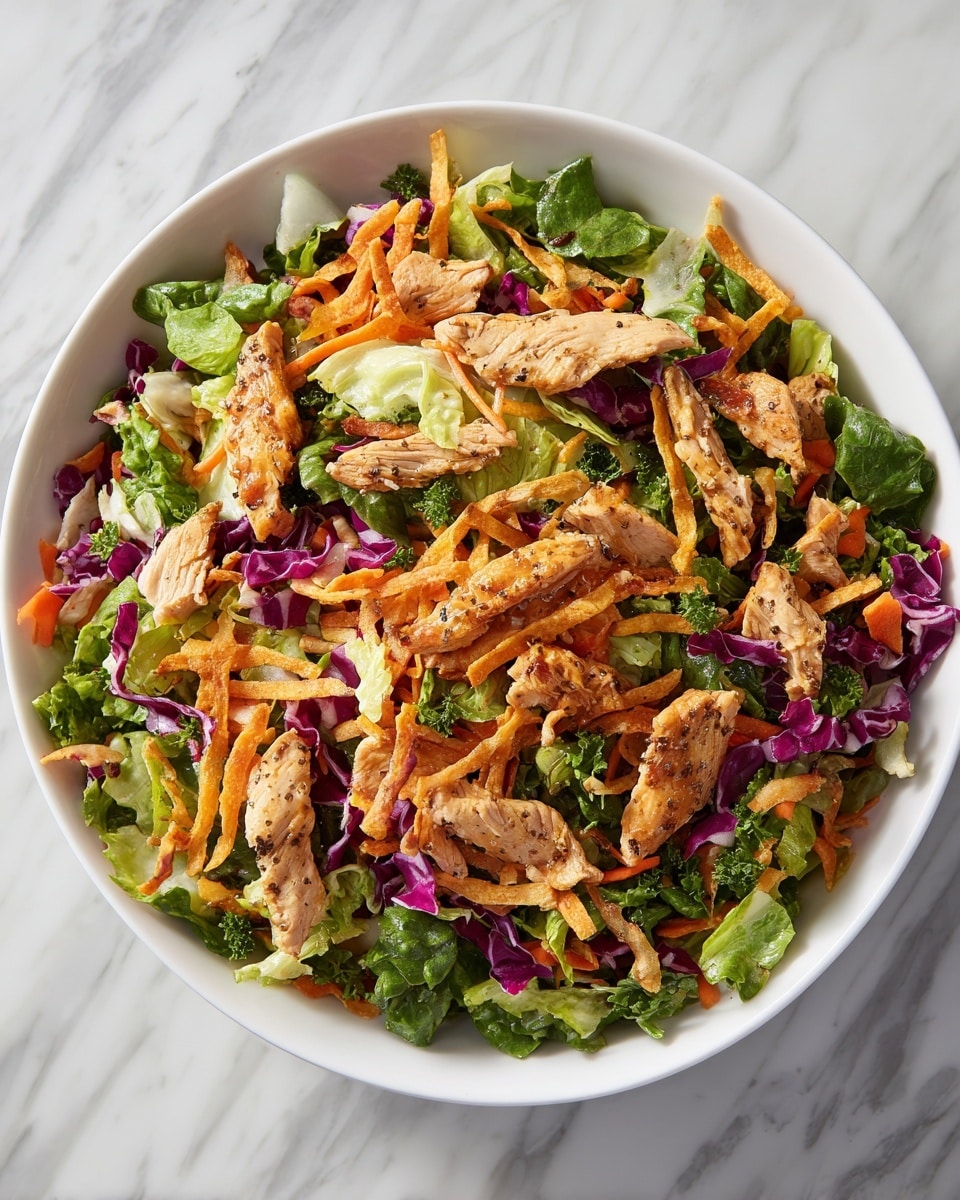 The dish is a colorful salad in a white bowl, placed on a surface with a white marbled texture. It has several layers starting with a base of mixed chopped greens including lettuce and cabbage in light green, purple, and orange shades. On top, there are golden crispy strips spread evenly throughout the salad. Scattered over these are pieces of cooked chicken, light golden brown with visible pepper seasoning. The salad looks fresh and vibrant with the mix of greens, orange carrots, crispy strips, and cooked chicken pieces. photo taken with an iphone --ar 4:5 --v 7
