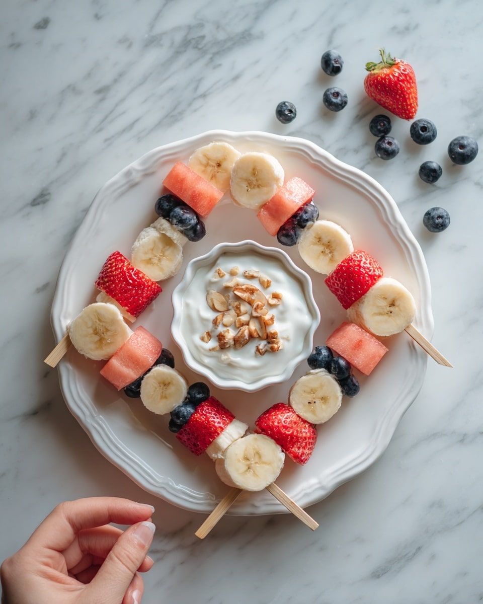The image shows a white plate on a white marbled surface, holding four fruit skewers arranged in a square. Each skewer has alternating pieces of red strawberries, light pink watermelon, and pale yellow banana slices. In the center of the plate, there is a white bowl with a wavy edge filled with white yogurt or dip, topped with small pieces of nuts. Blueberries are scattered around the plate and surface. A woman's hand reaches from the top left side, holding one of the skewers. Photo taken with an iphone --ar 4:5 --v 7
