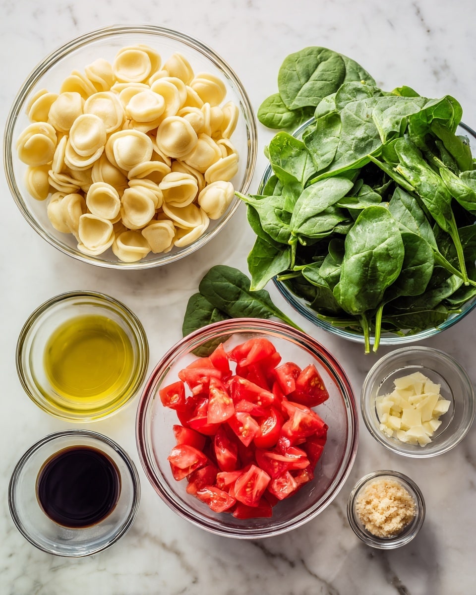 The image shows six bowls on a white marbled surface. The largest clear bowl at the back left is filled with pale yellow orecchiette pasta. Next to it on the right, there is a big pile of fresh green spinach leaves. In front, there are four smaller clear bowls arranged in a loose cluster: chopped red tomatoes fill a medium bowl in the center, a dark brown liquid (balsamic vinegar) in a small bowl to the left, light yellow olive oil in another small bowl at the bottom, and a tiny clear bowl to the right contains a light brown paste (minced garlic). The colors are bright and fresh, with the greens and reds contrasting well with the neutral tones of the pasta and liquids. Photo taken with an iphone --ar 4:5 --v 7