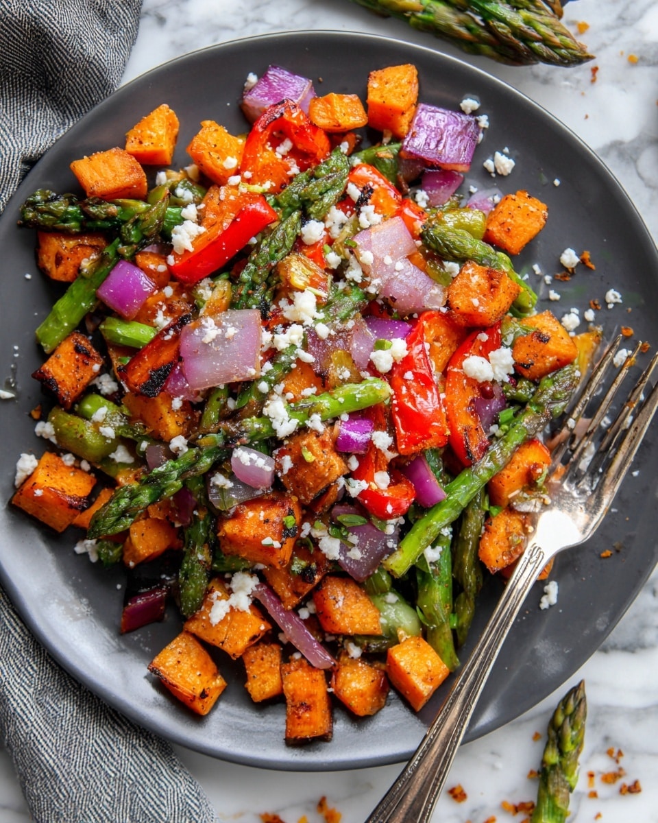The image shows a dark gray round plate filled with a colorful mix of roasted vegetables. The dish has three main layers: the bottom layer consists of small cubed orange sweet potatoes with a slightly charred texture; the middle layer contains bright red bell pepper pieces and green asparagus spears, both roasted with a slightly darkened, crisp look; the top layer is scattered with small chunks of light purple onion and white crumbled cheese that adds a contrasting texture. The plate is placed on a white marbled surface with some bits of onion, asparagus, and cheese scattered around it. A shiny metallic fork rests on the plate, partially inserted into the vegetables. The overall look is vibrant with a mix of deep reds, greens, purples, and whites, showing a rustic roasted vegetable medley. photo taken with an iphone --ar 4:5 --v 7